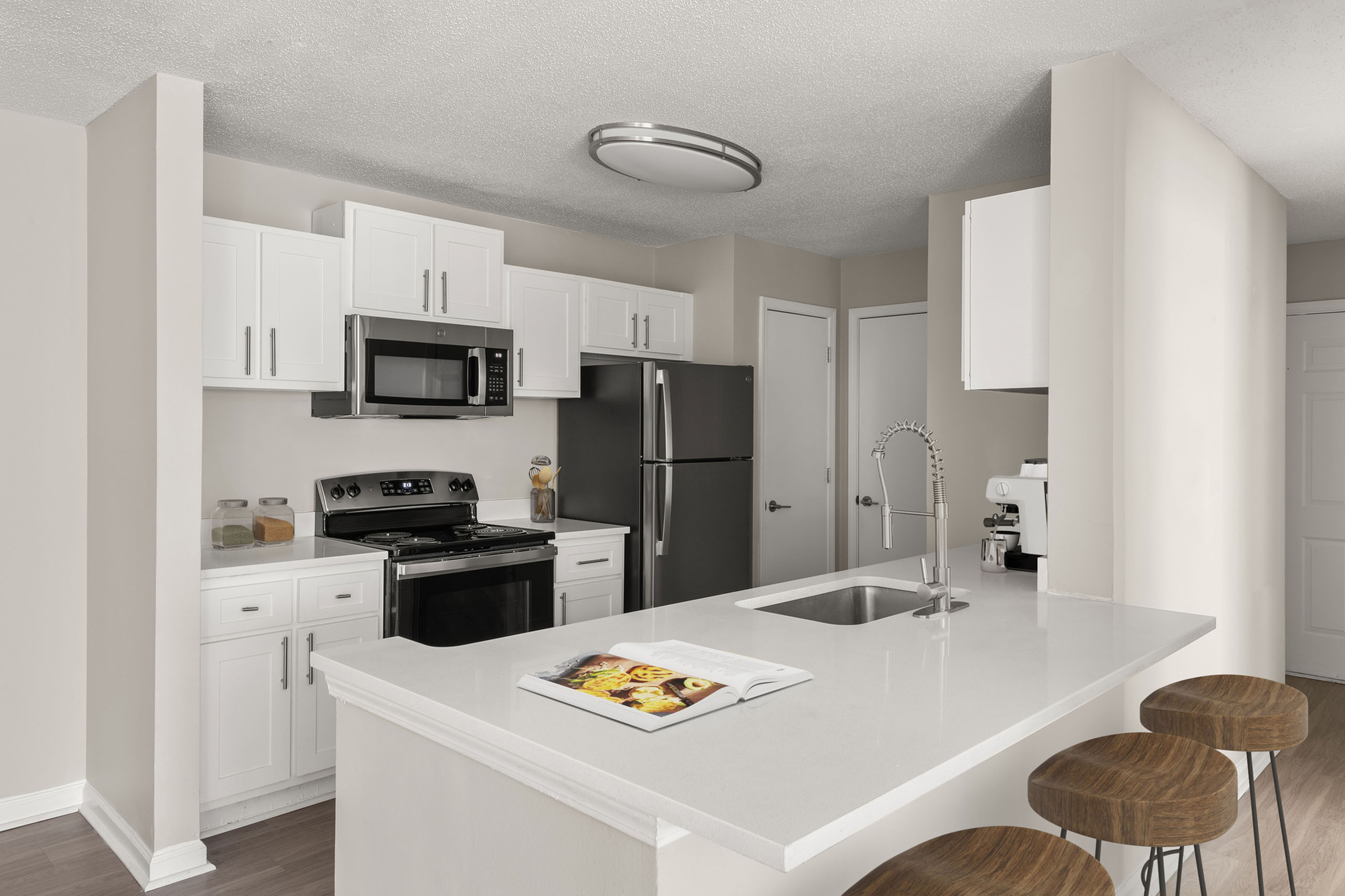 Modern kitchen with sleek white cabinetry, stainless steel appliances, and a chic breakfast bar with wooden stools.