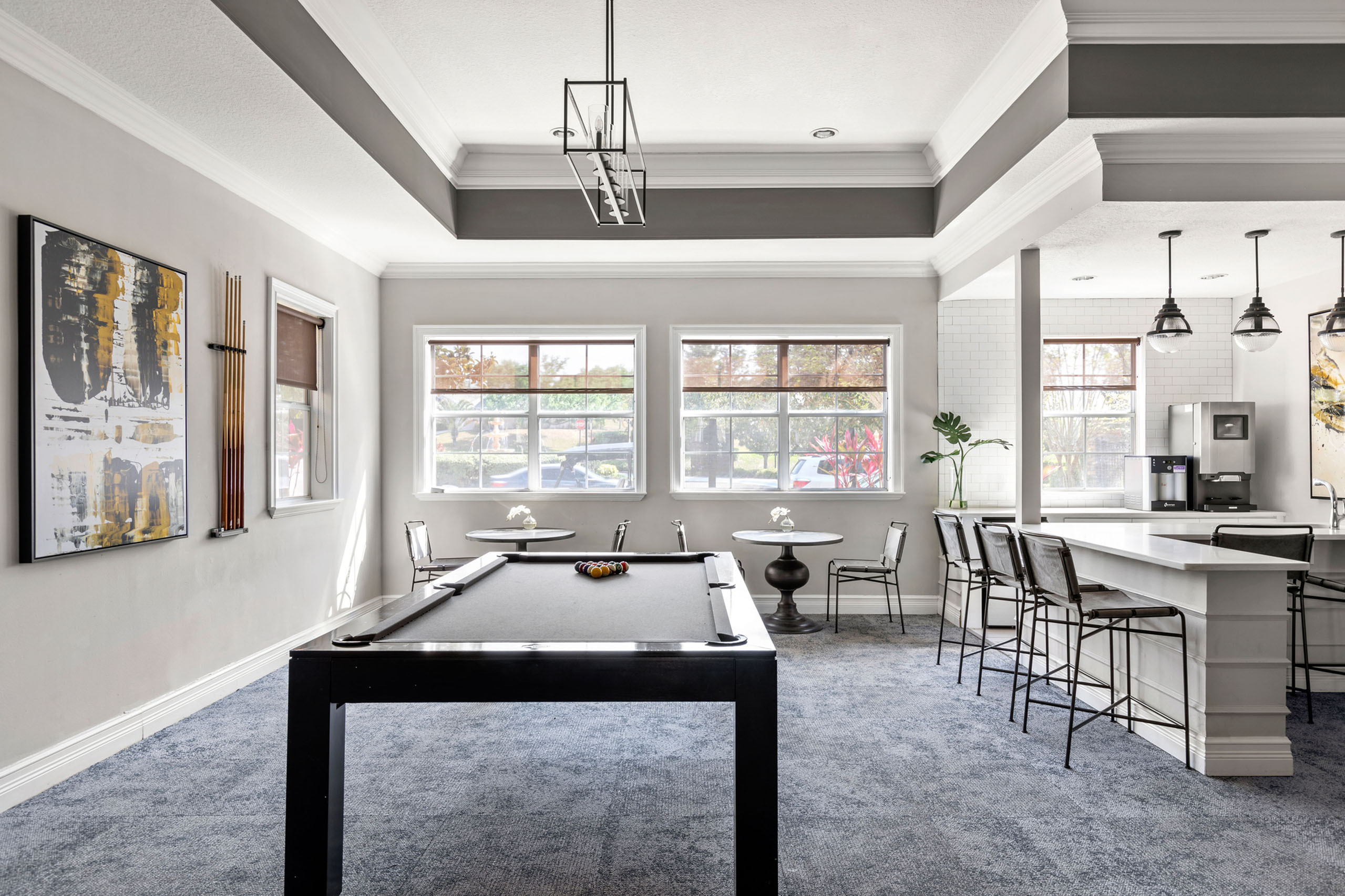 Elegant recreation area with a pool table, modern bar seating, and large windows for natural light.