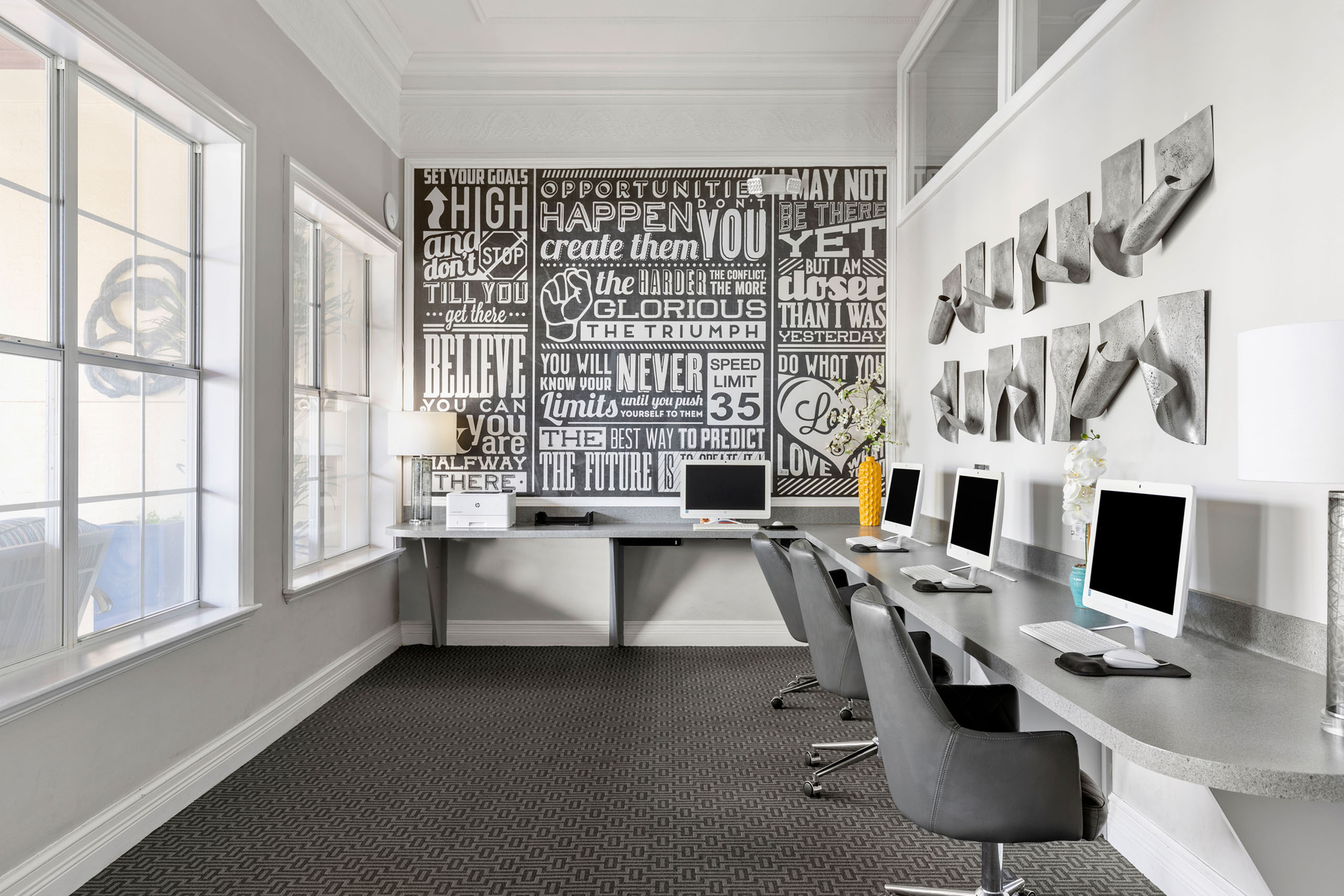 Chic and modern home office with sleek design, inspirational wall art, ample natural light, stylish workstations, and cozy seating.