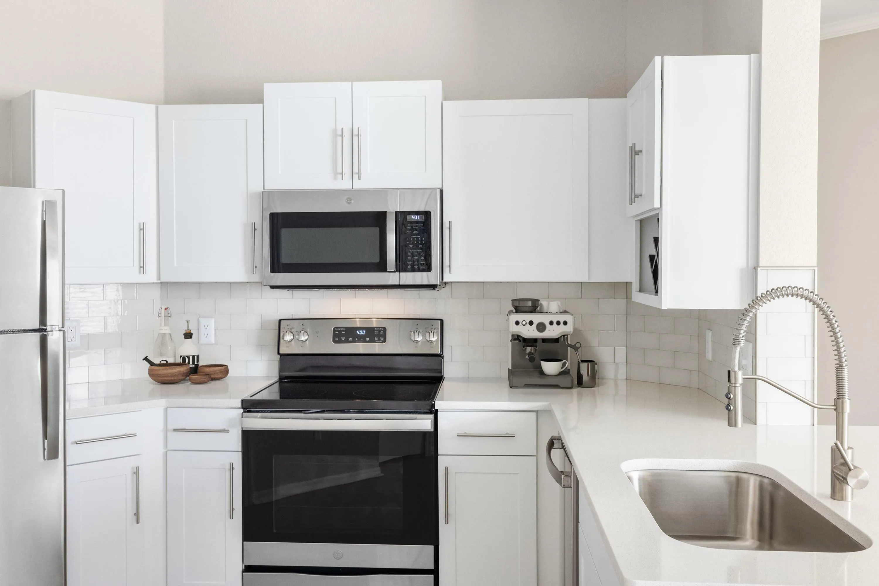 Modern kitchen with sleek white cabinetry, stainless steel appliances, and elegant countertop, perfect for culinary enthusiasts.