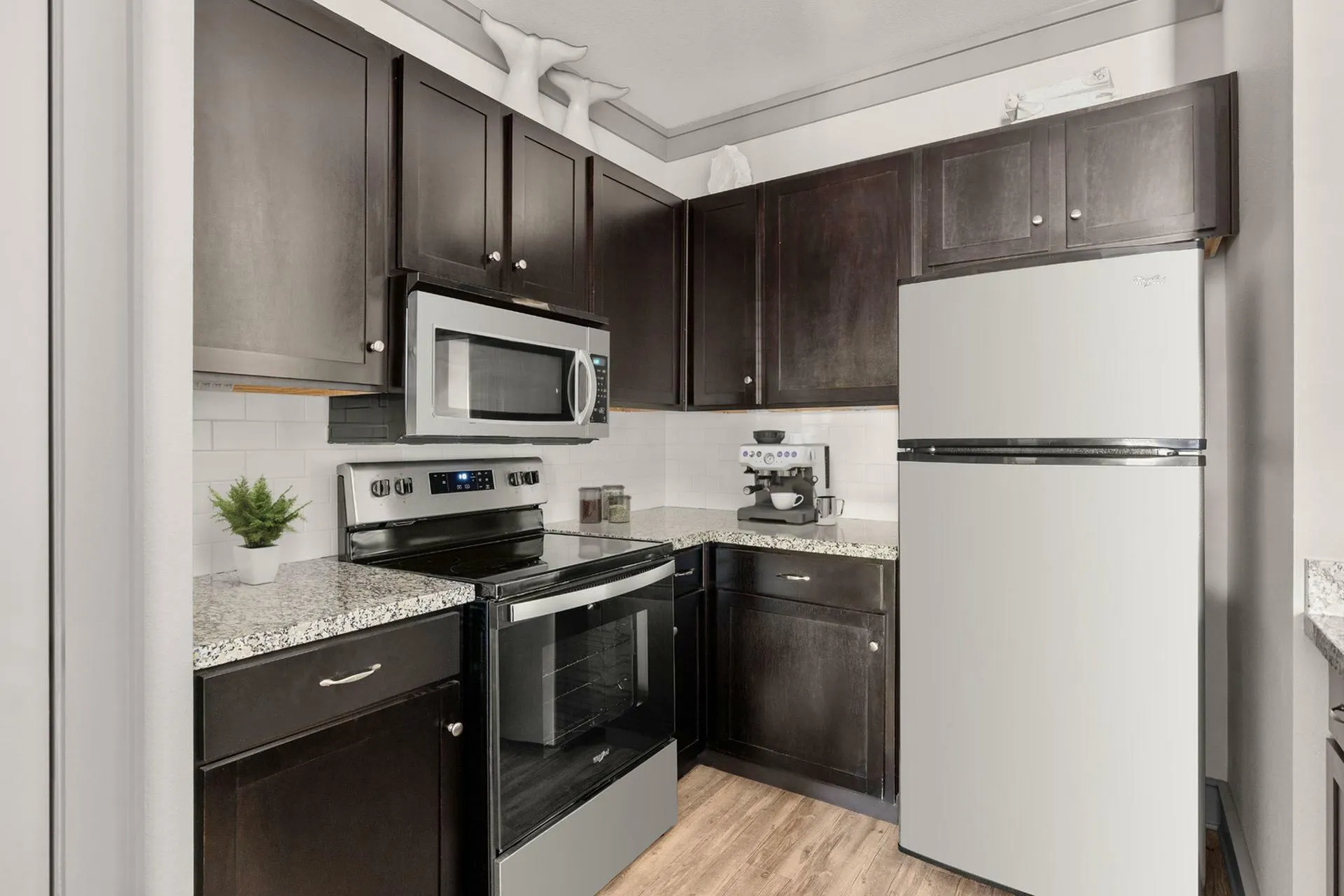 Modern kitchen with dark wood cabinets, sleek appliances, and stylish granite countertops, perfect for home chefs.