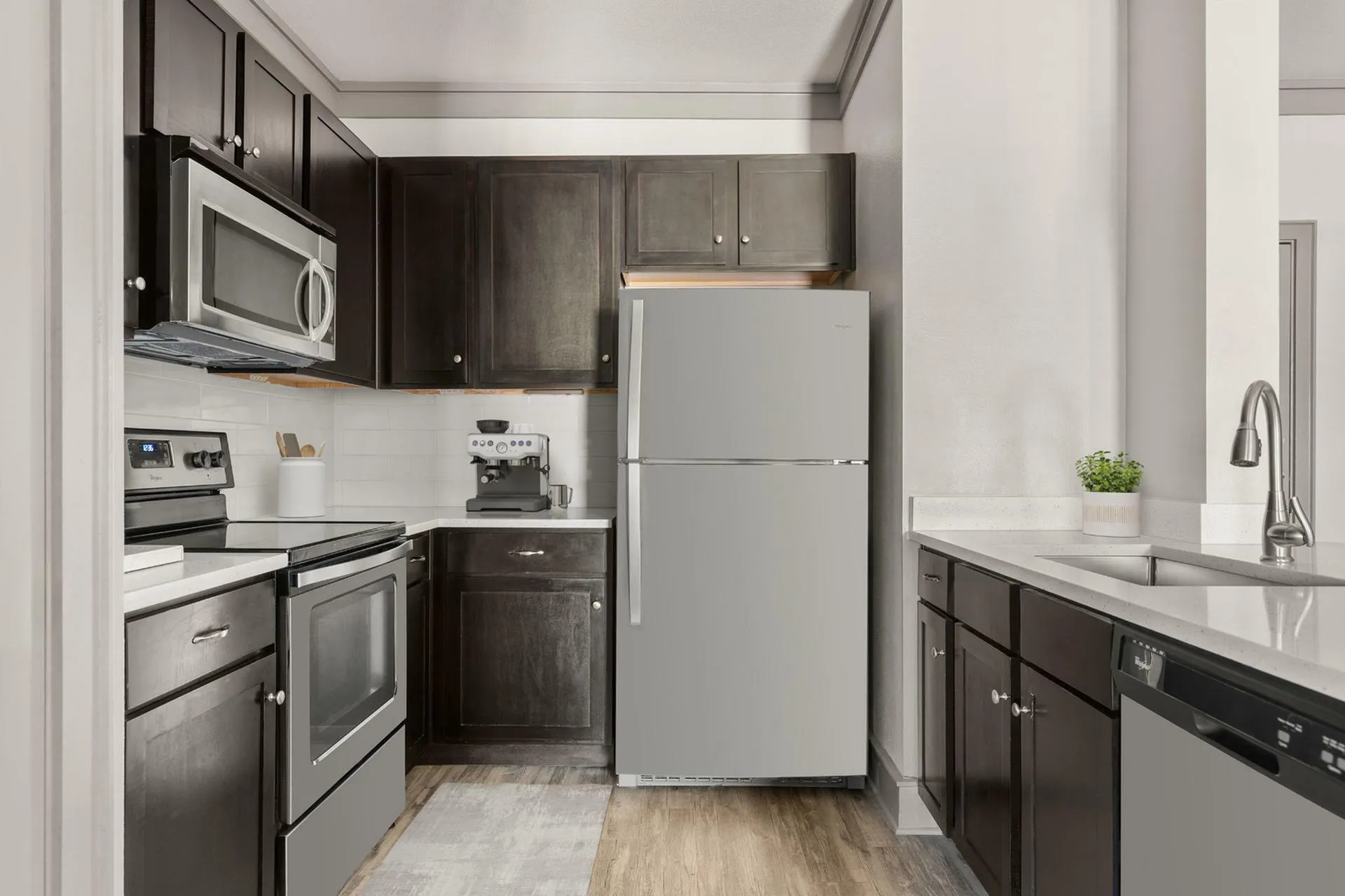 Modern kitchen with sleek dark cabinets, stainless steel appliances, and elegant countertops, offering a stylish and functional cooking space.