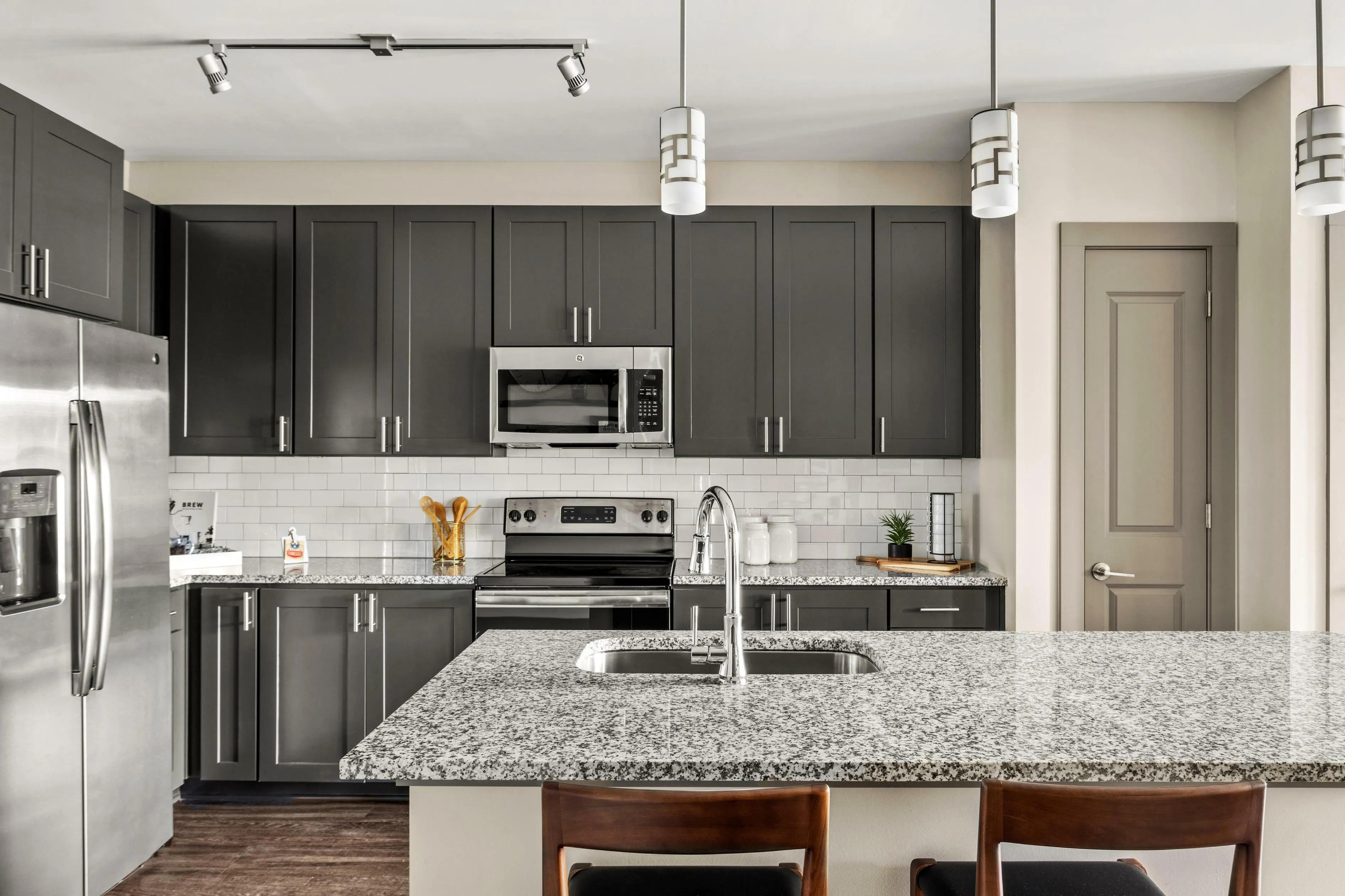 Modern kitchen with elegant gray cabinets, sleek stainless steel appliances, and a stylish granite island, creating a sophisticated culinary space.