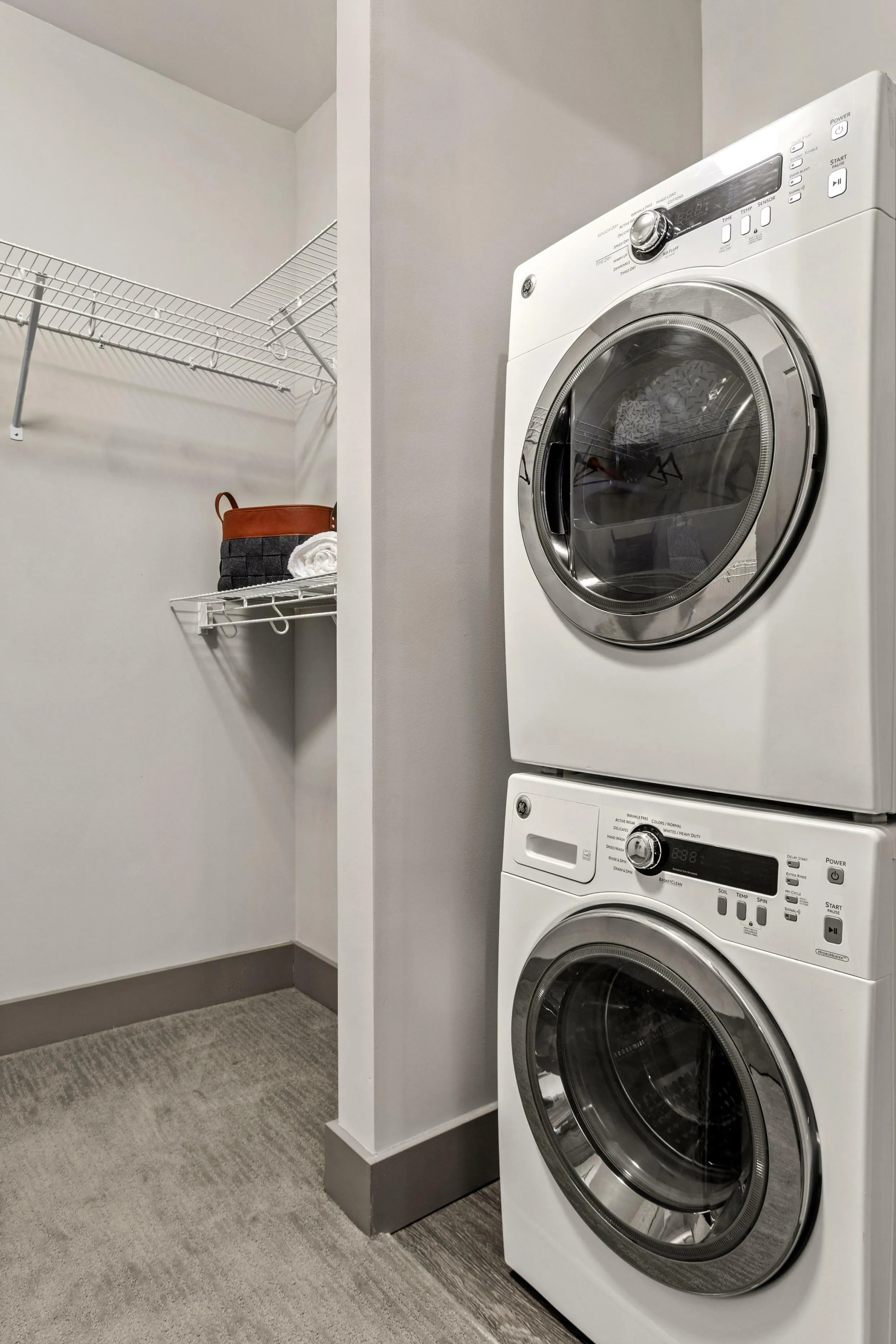 Modern laundry room with sleek stacked washer and dryer, featuring ample wire shelving for organized storage.
