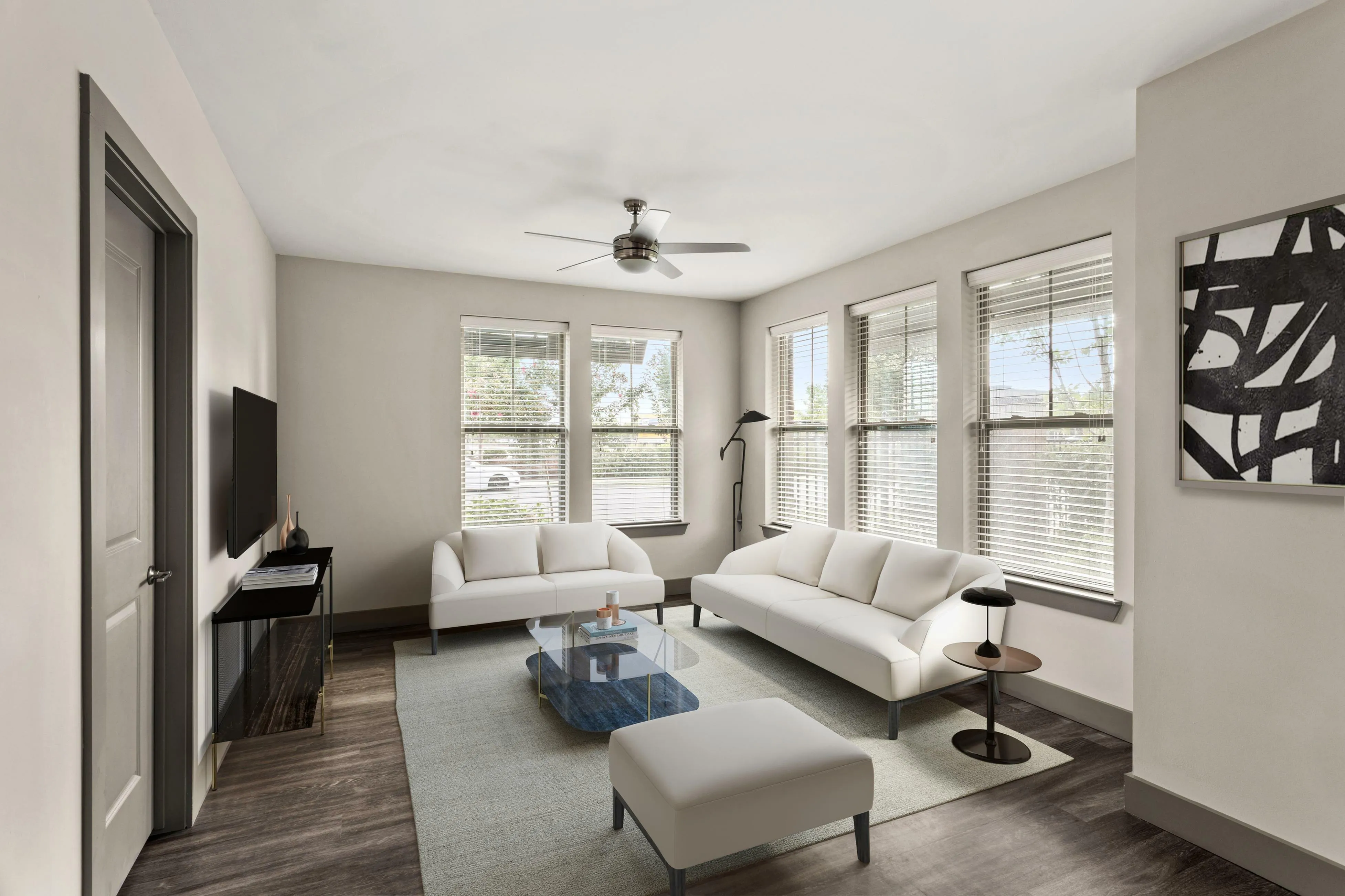 Modern living room with sleek gray flooring, stylish white sofas, a glass coffee table, and abundant natural light from multiple windows.