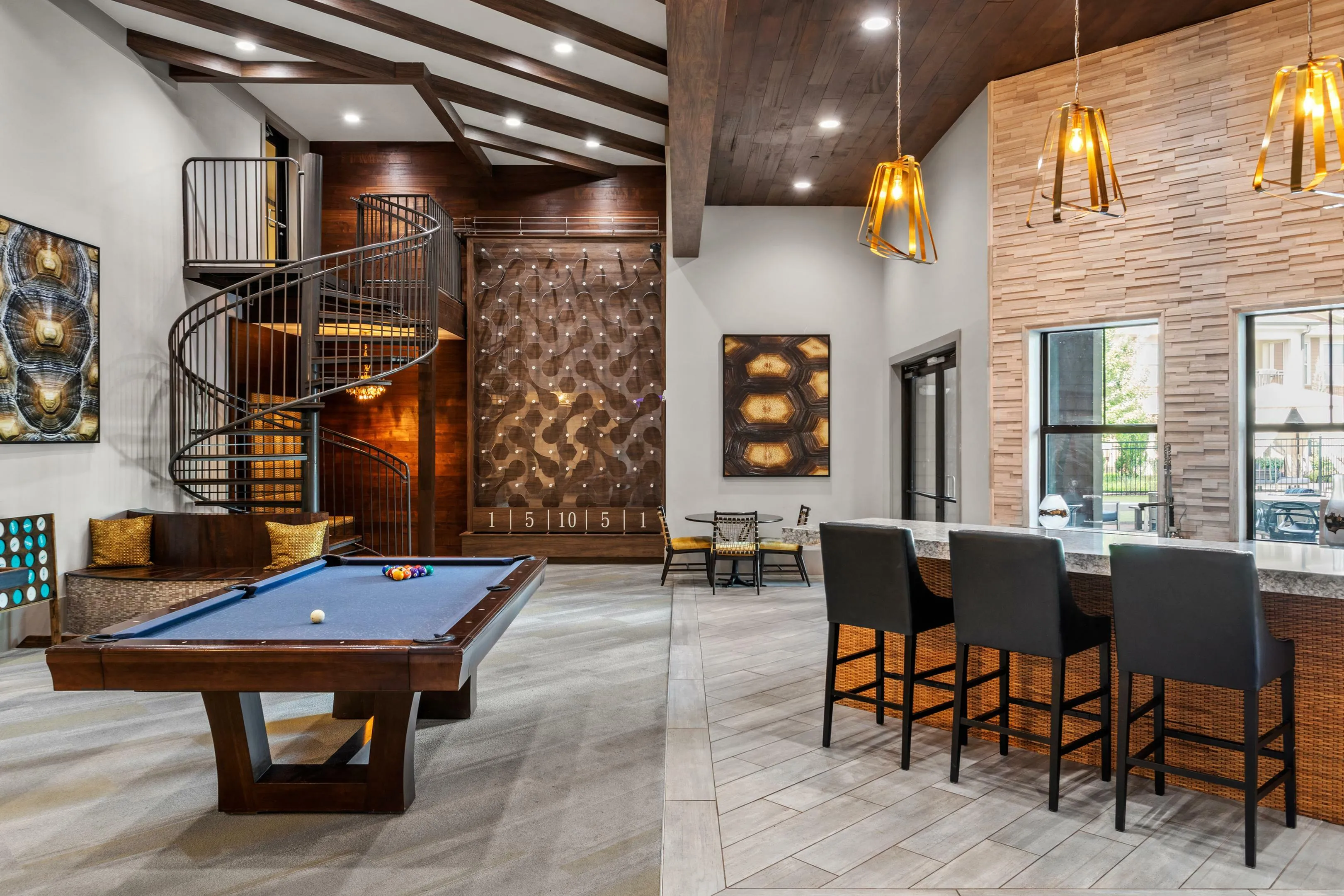 Luxurious recreation room with a sleek spiral staircase, billiards table, and modern bar seating under elegant lighting.