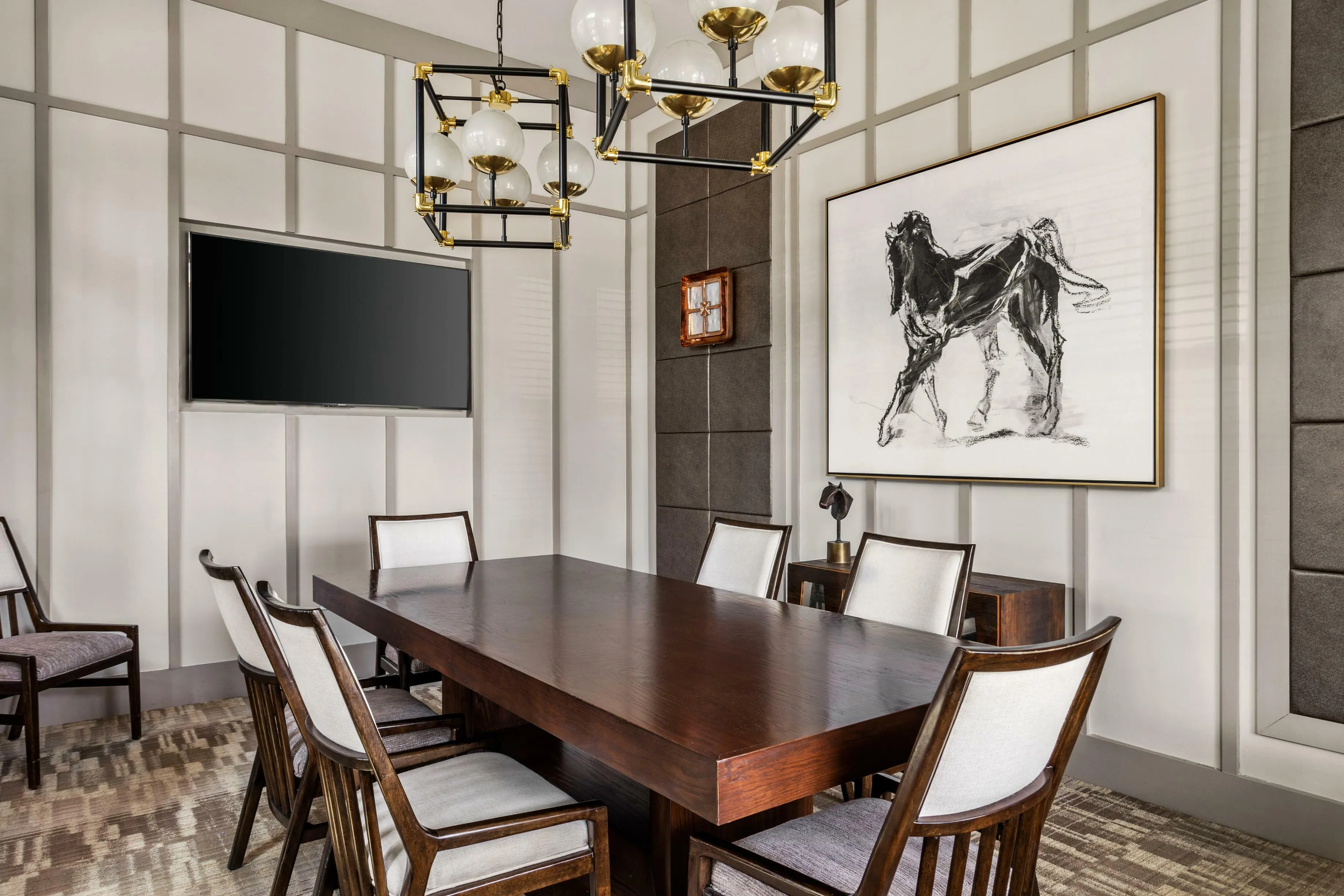 Elegant dining area with a chic wooden table, modern chandelier, and horse artwork, perfect for sophisticated gatherings.