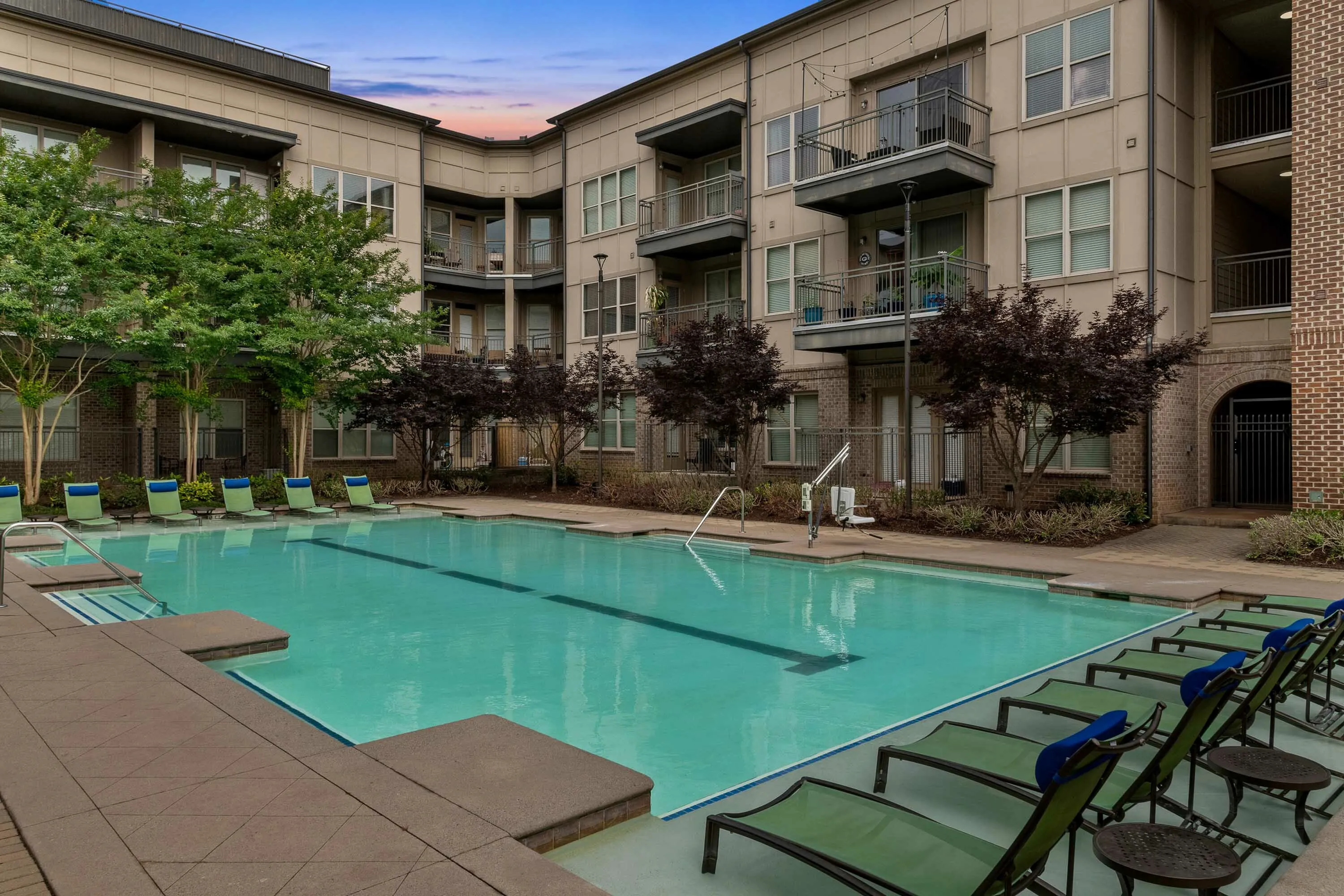 Luxurious apartment complex with a serene swimming pool surrounded by lush greenery and modern balconies, perfect for relaxation and leisure.