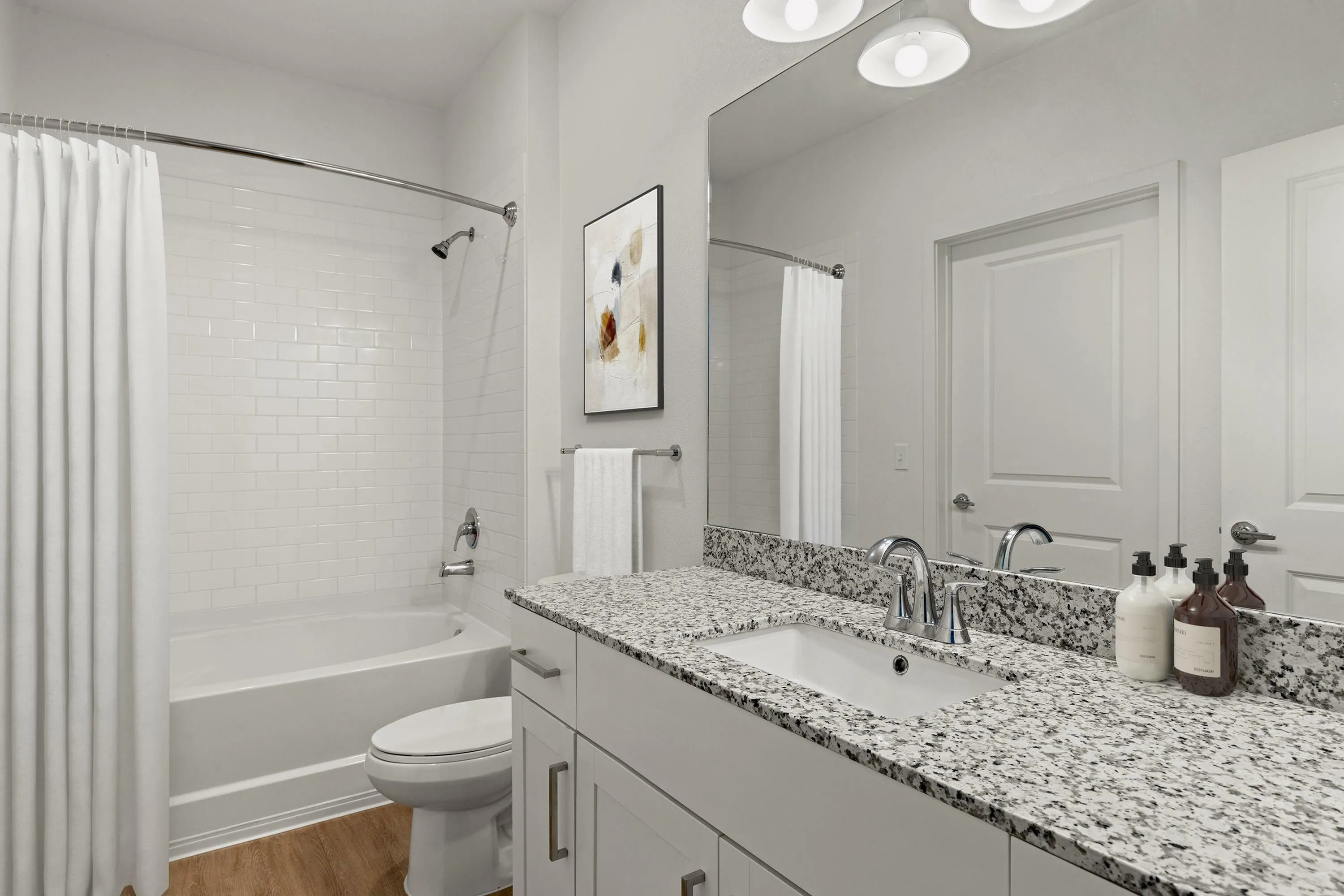 Elegant bathroom with modern granite countertop, bright lighting, and a pristine white bathtub, offering a refreshing and sophisticated space.