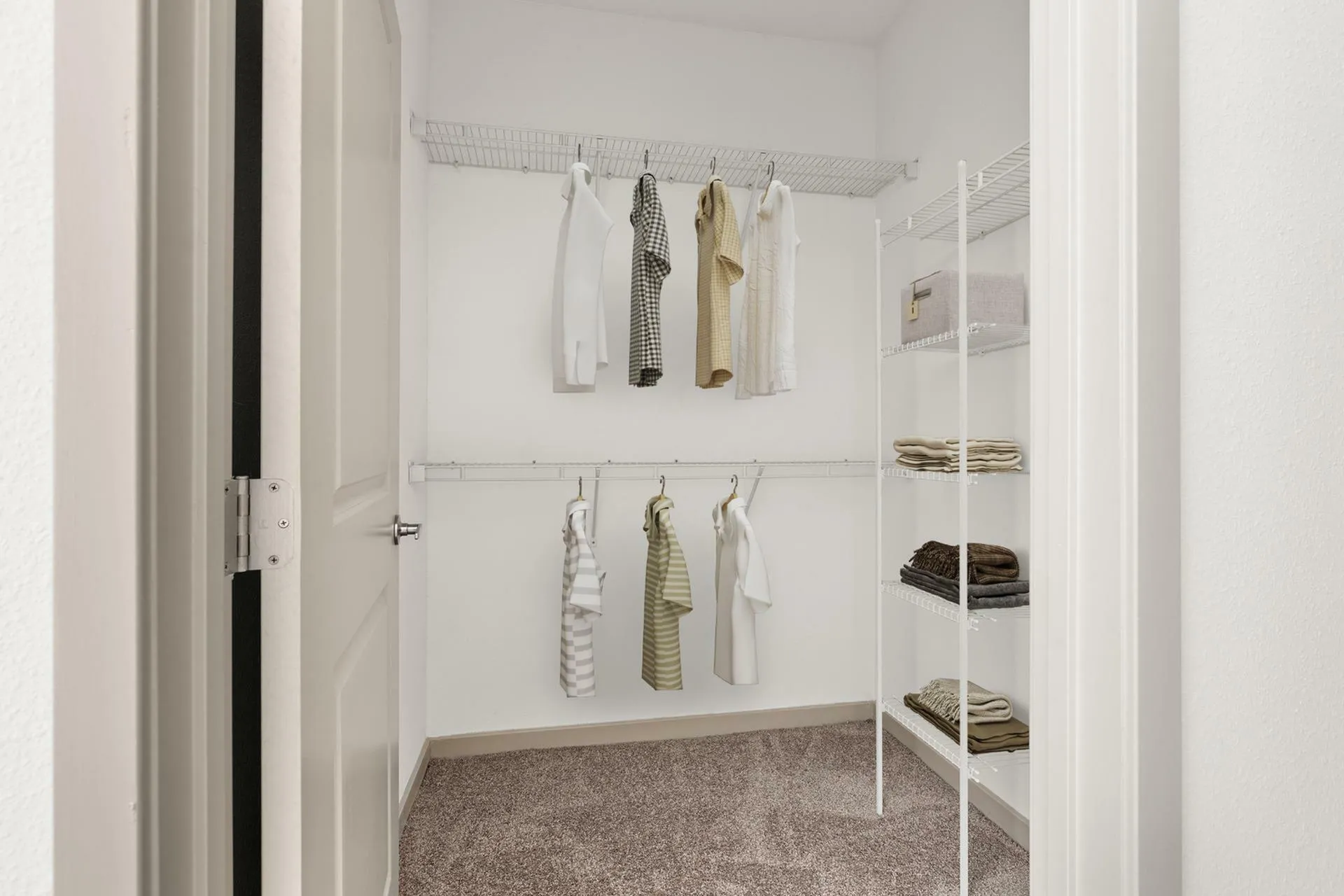 Spacious walk-in closet with shelves and neatly organized clothing.