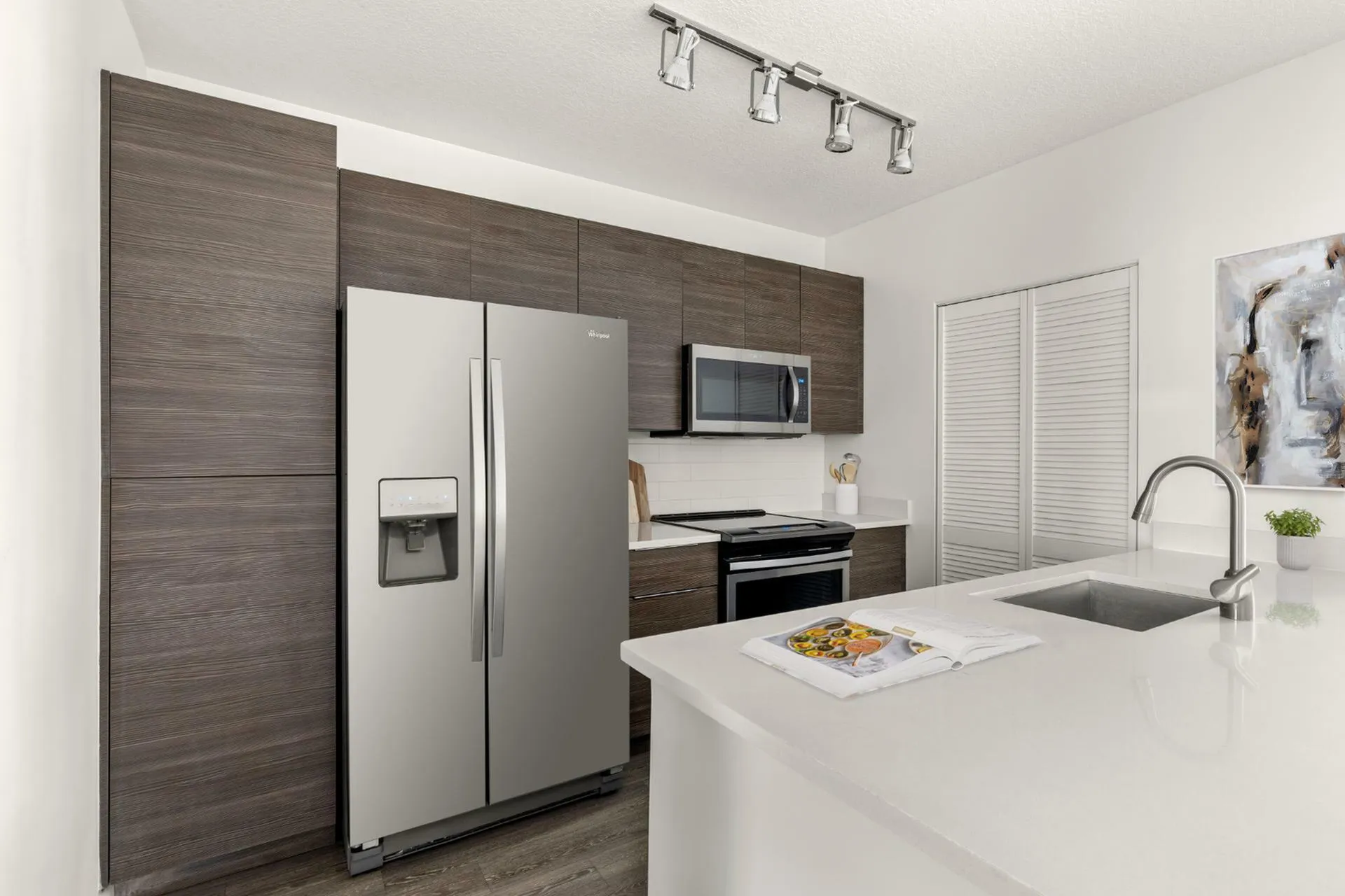 Sleek modern kitchen featuring stainless steel appliances, elegant dark wood cabinets, and a chic, white countertop island with stylish lighting.