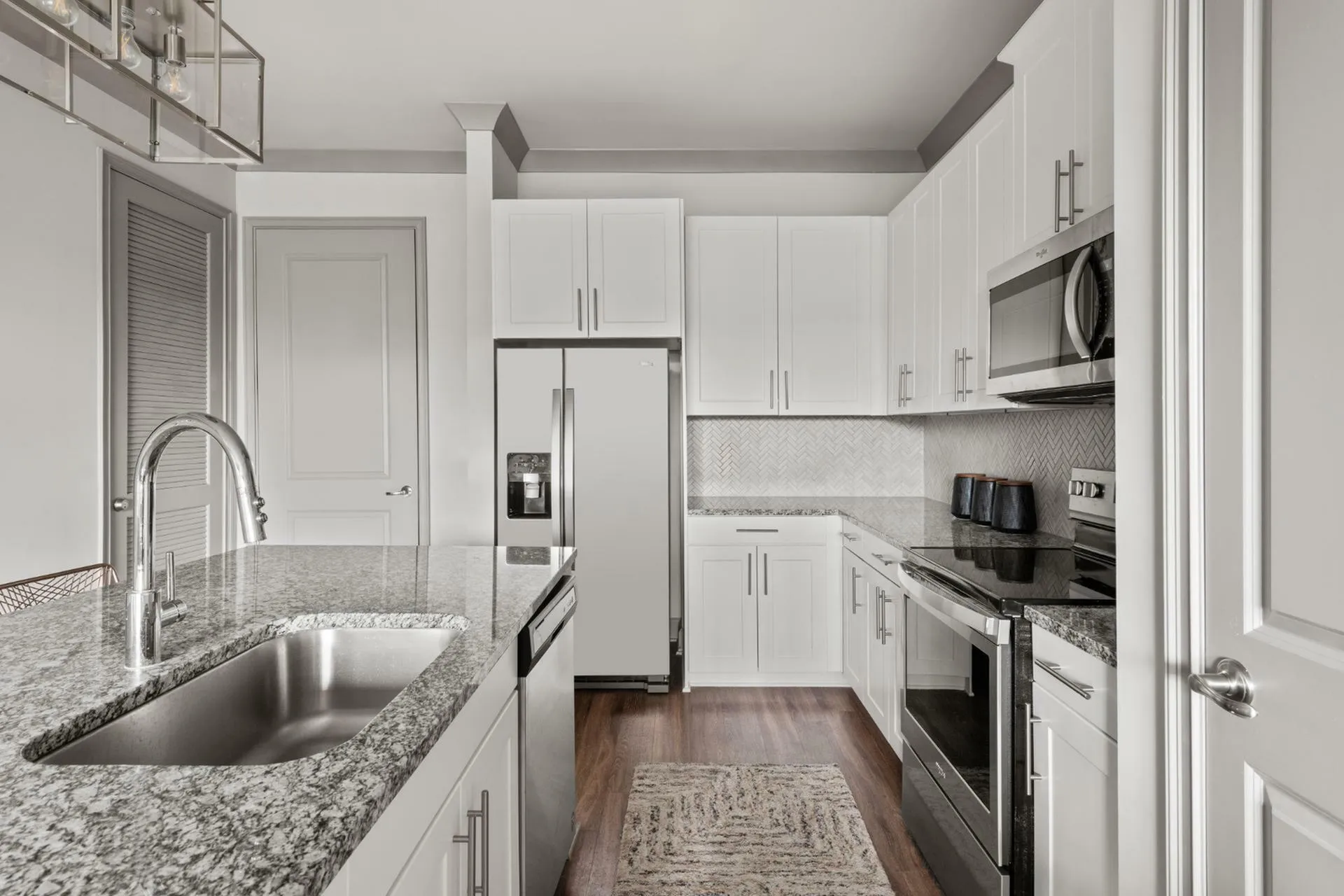 Sleek modern kitchen with granite countertops, stainless steel appliances, and elegant white cabinetry.