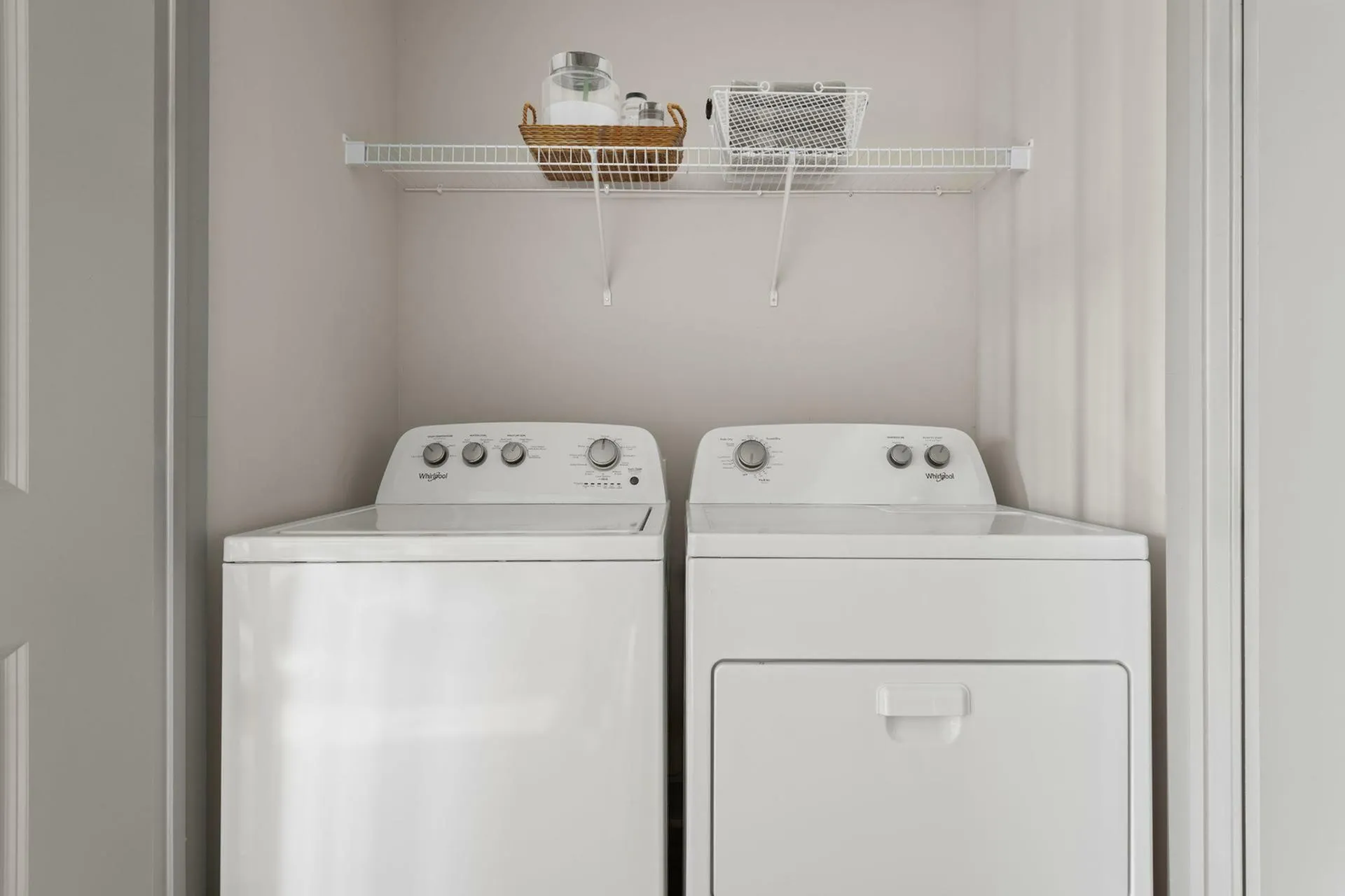 Modern laundry space with efficient washer and dryer set, featuring convenient overhead shelving.