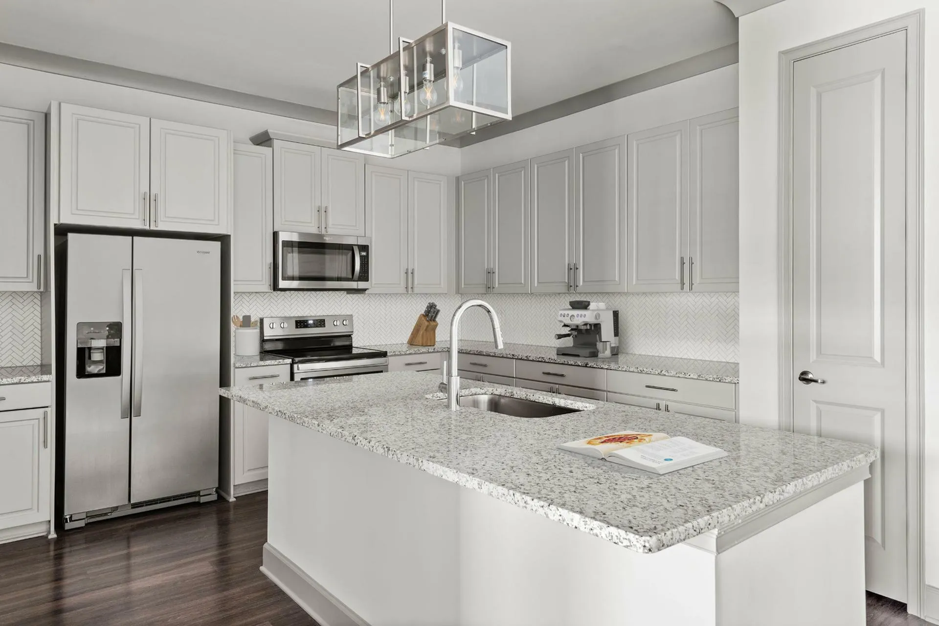 Elegant modern kitchen with sleek white cabinetry, stainless steel appliances, and a spacious granite island, perfect for culinary adventures.