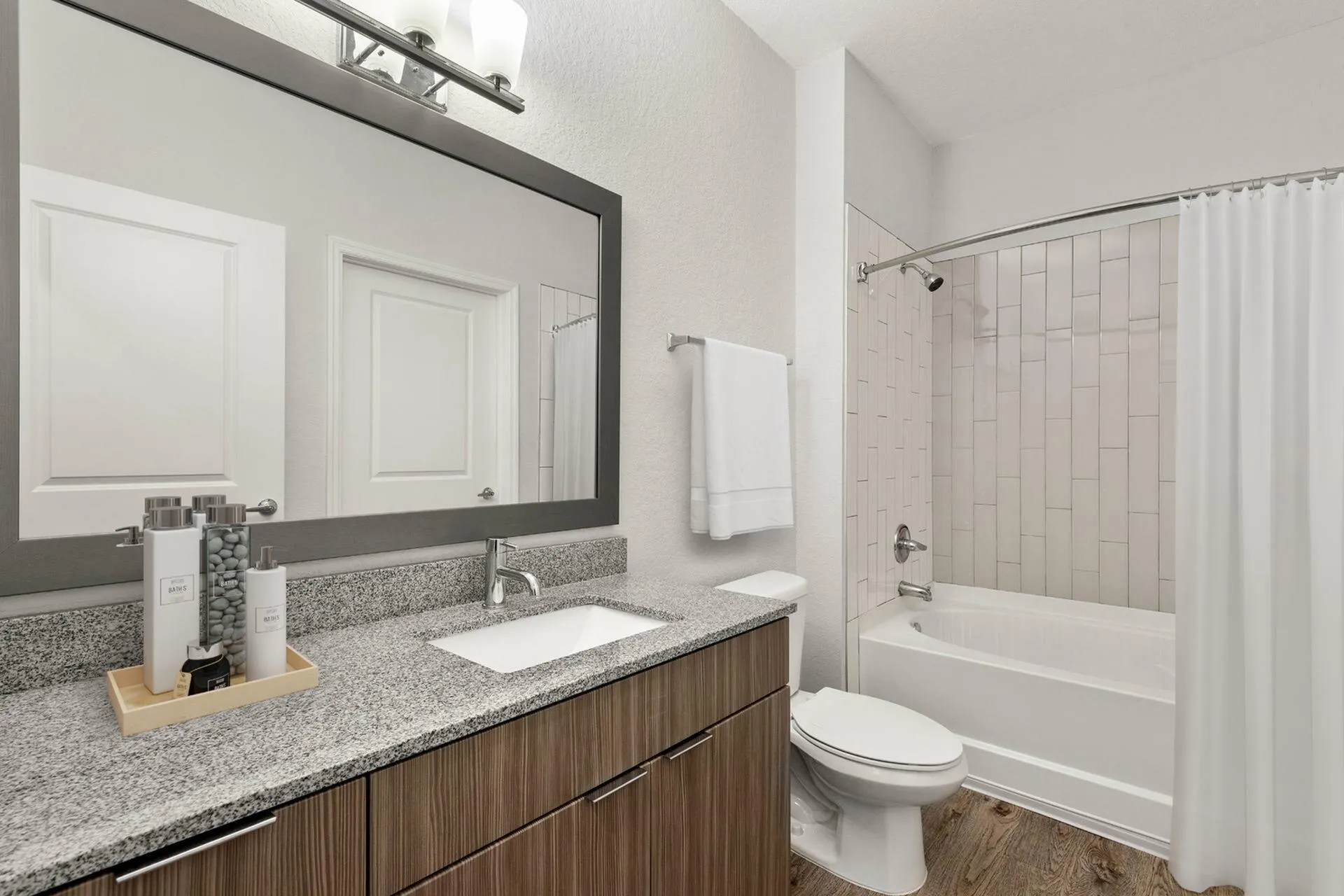 Sleek modern bathroom with granite countertop, stylish vanity, and a chic bathtub with elegant tiles.