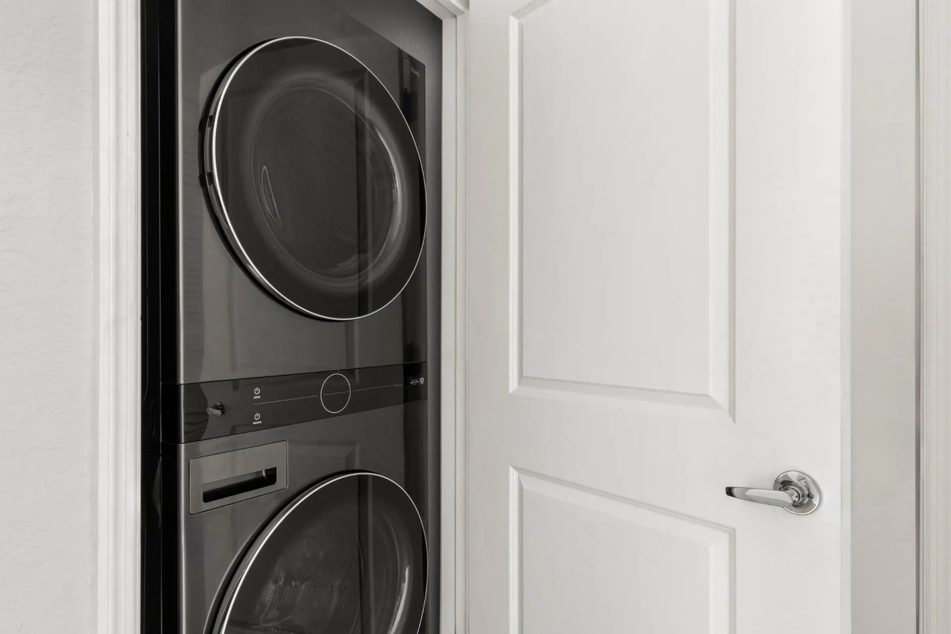 Sleek and modern stacked washer and dryer set tucked neatly behind a white door, maximizing space and efficiency.
