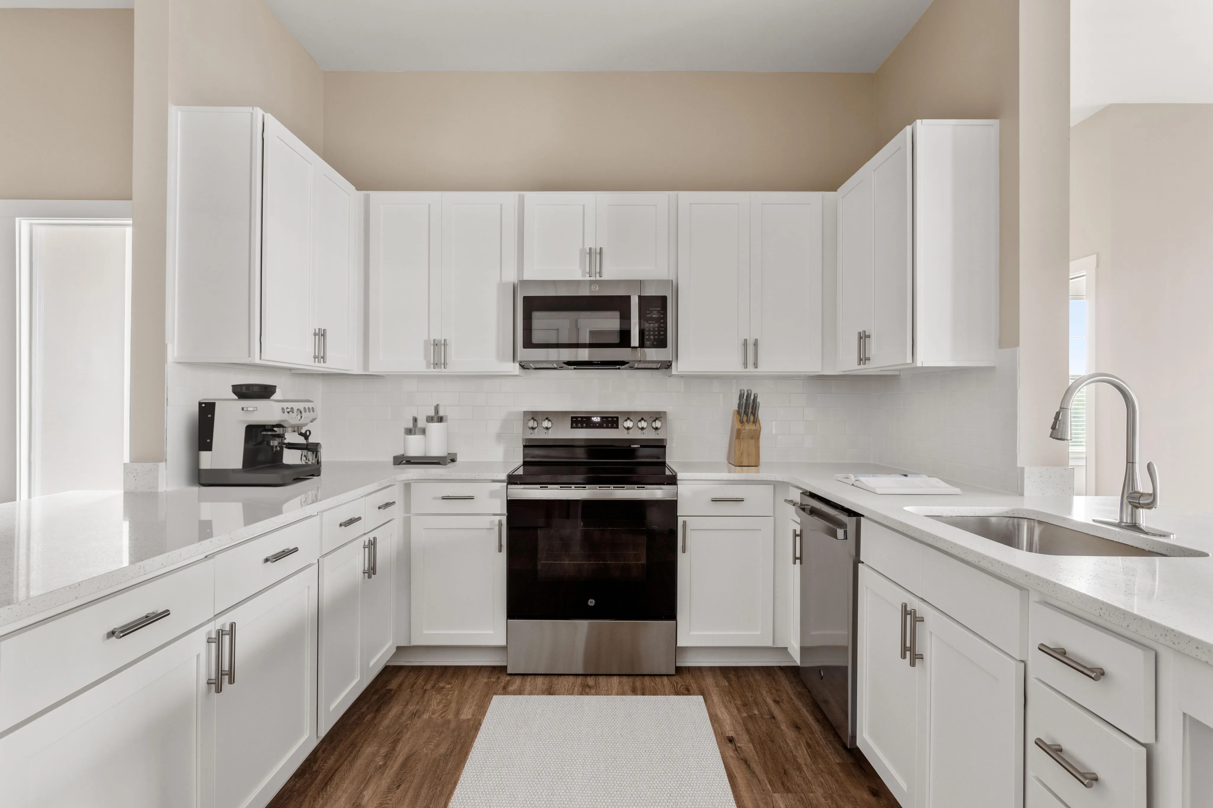 Sleek modern kitchen with white cabinetry, stainless steel appliances, and elegant wood flooring.