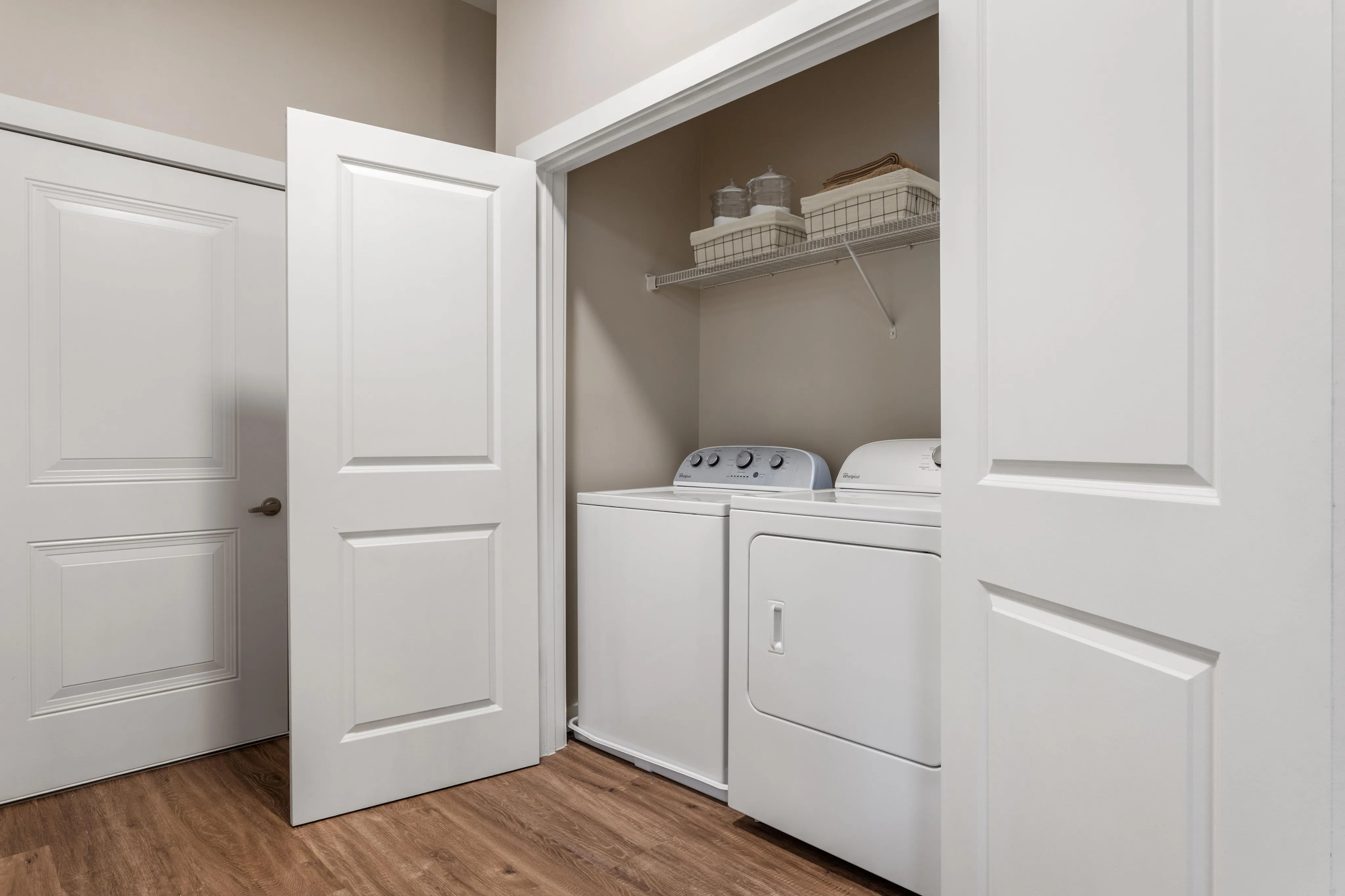 Modern laundry nook with sleek appliances, built-in shelving, and elegant wood flooring, perfect for convenience and style.