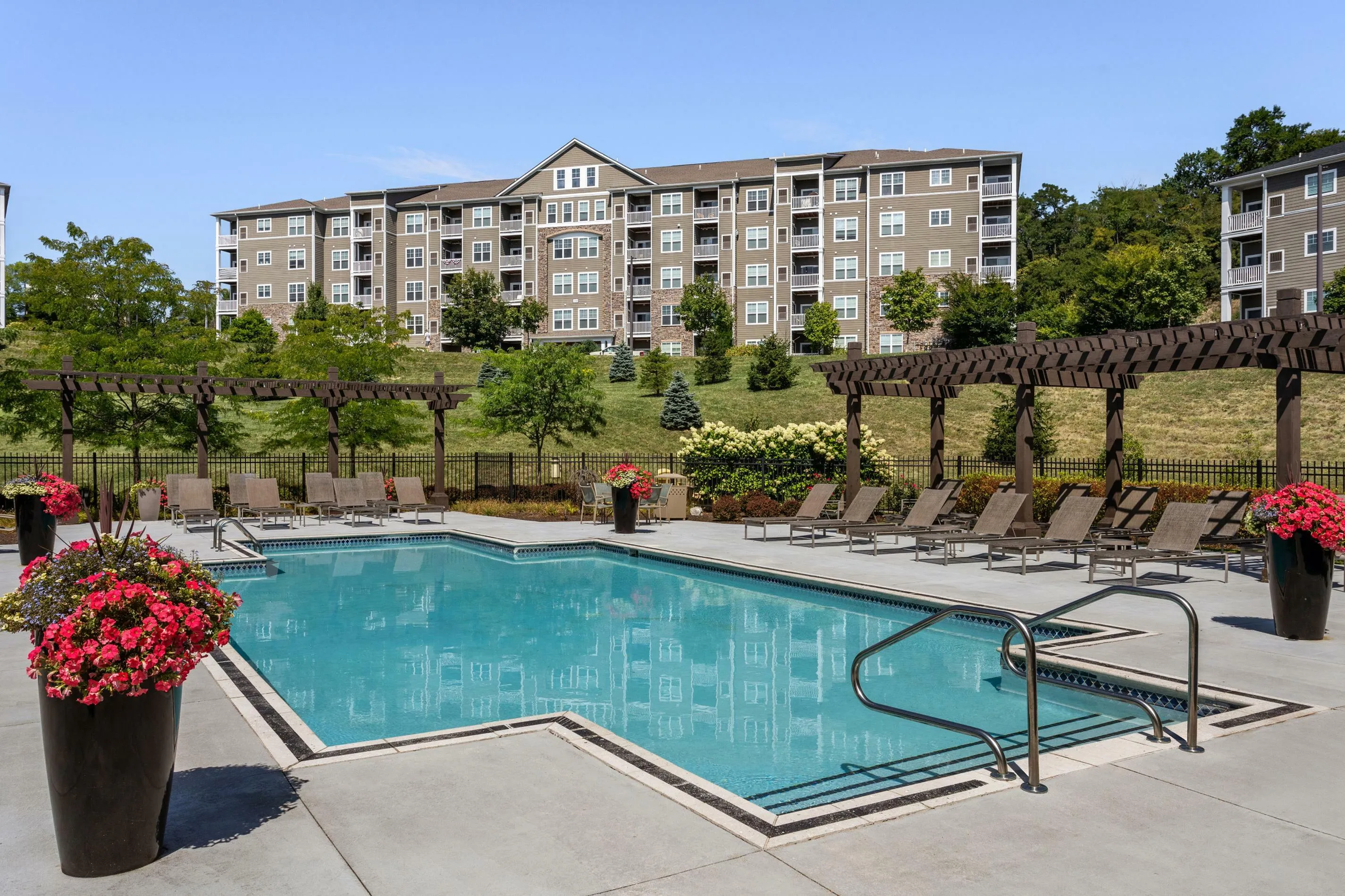 Inviting residential community with a sparkling pool, elegant loungers, and lush landscaping, offering a serene oasis for relaxation.