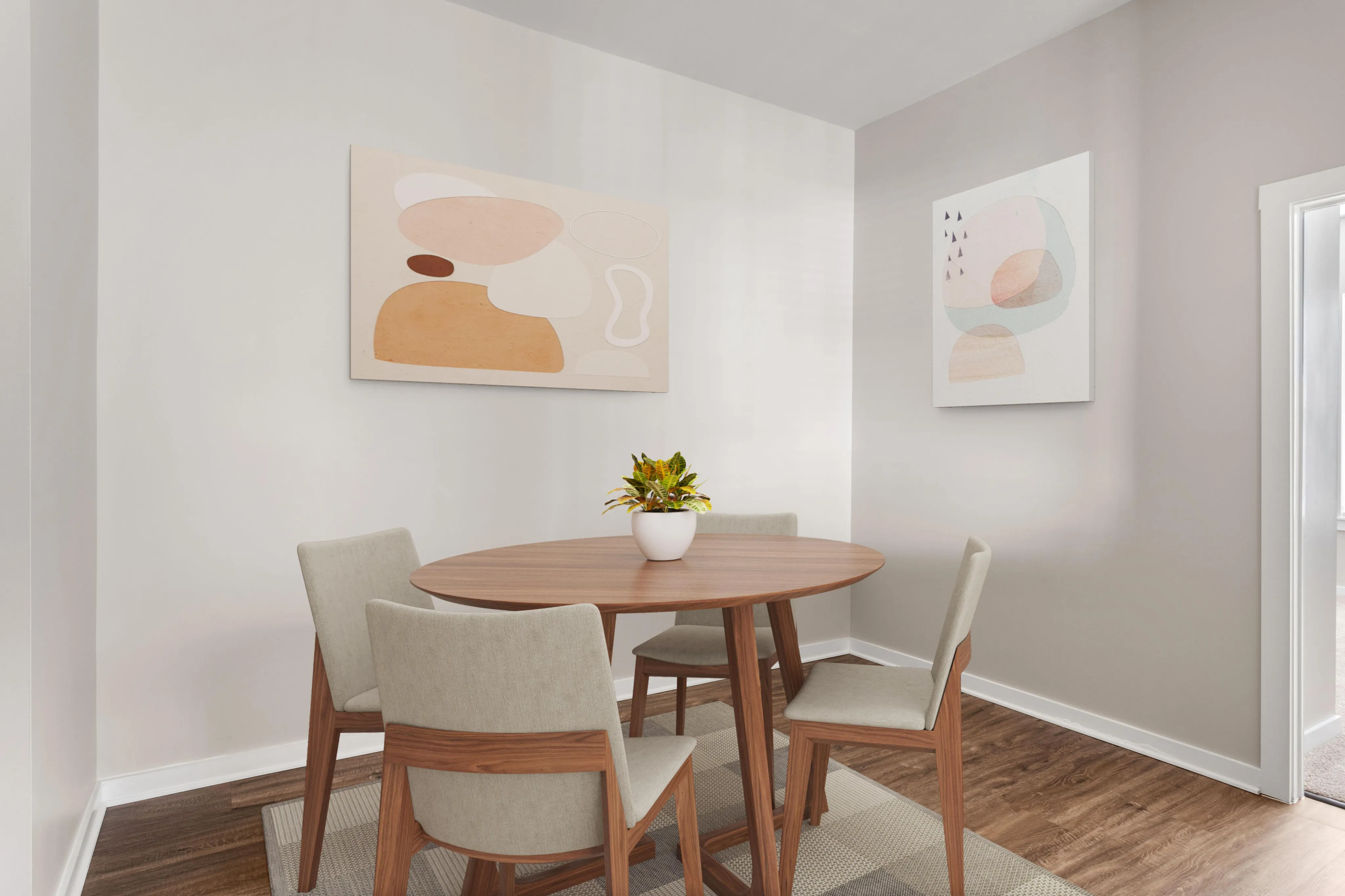 Contemporary dining area with a stylish round wooden table, comfortable beige chairs, and modern abstract artwork on light walls.