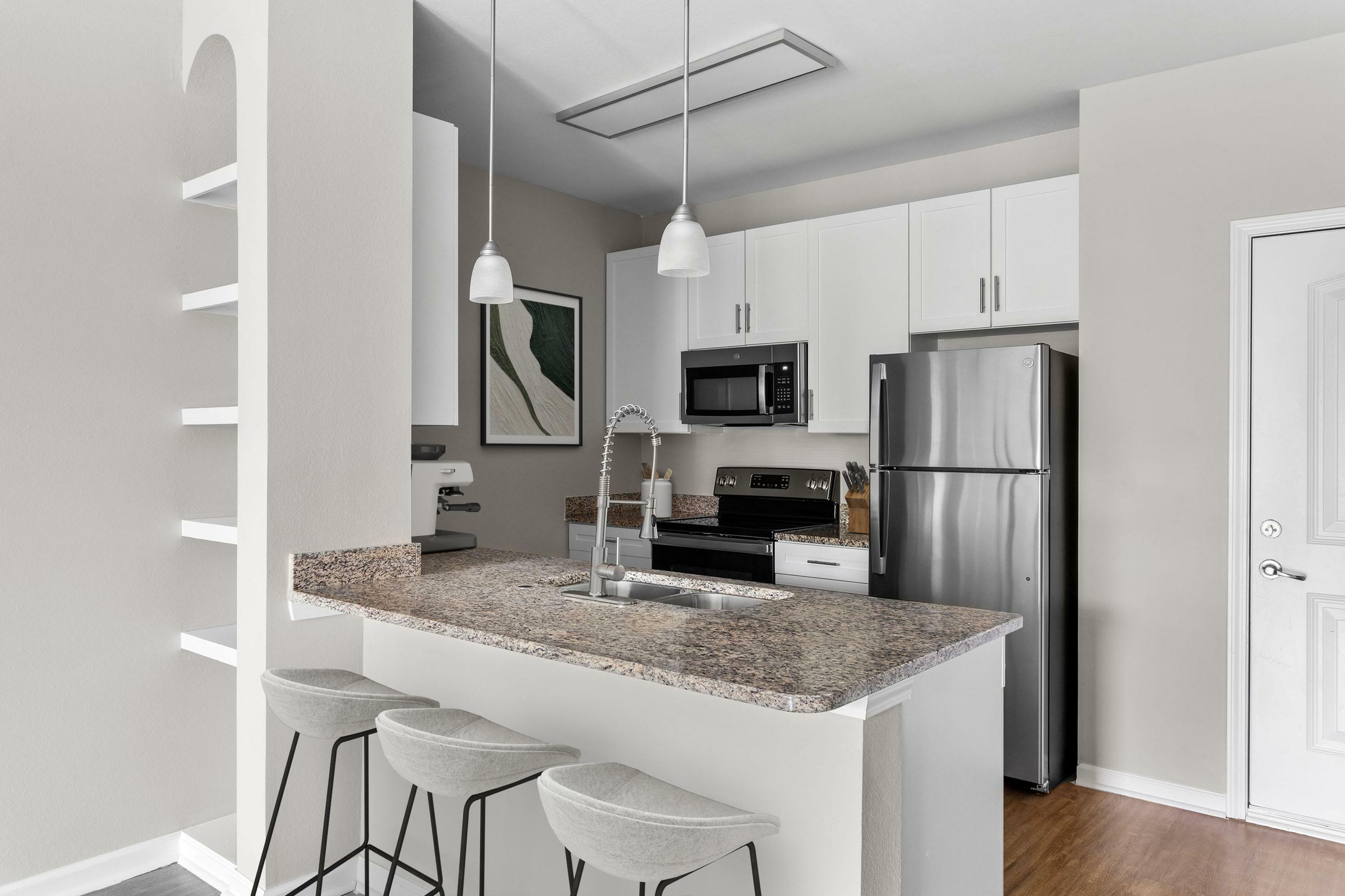 Modern kitchen with sleek granite countertops, stainless steel appliances, and elegant pendant lighting, featuring a chic breakfast bar with comfortable seating.