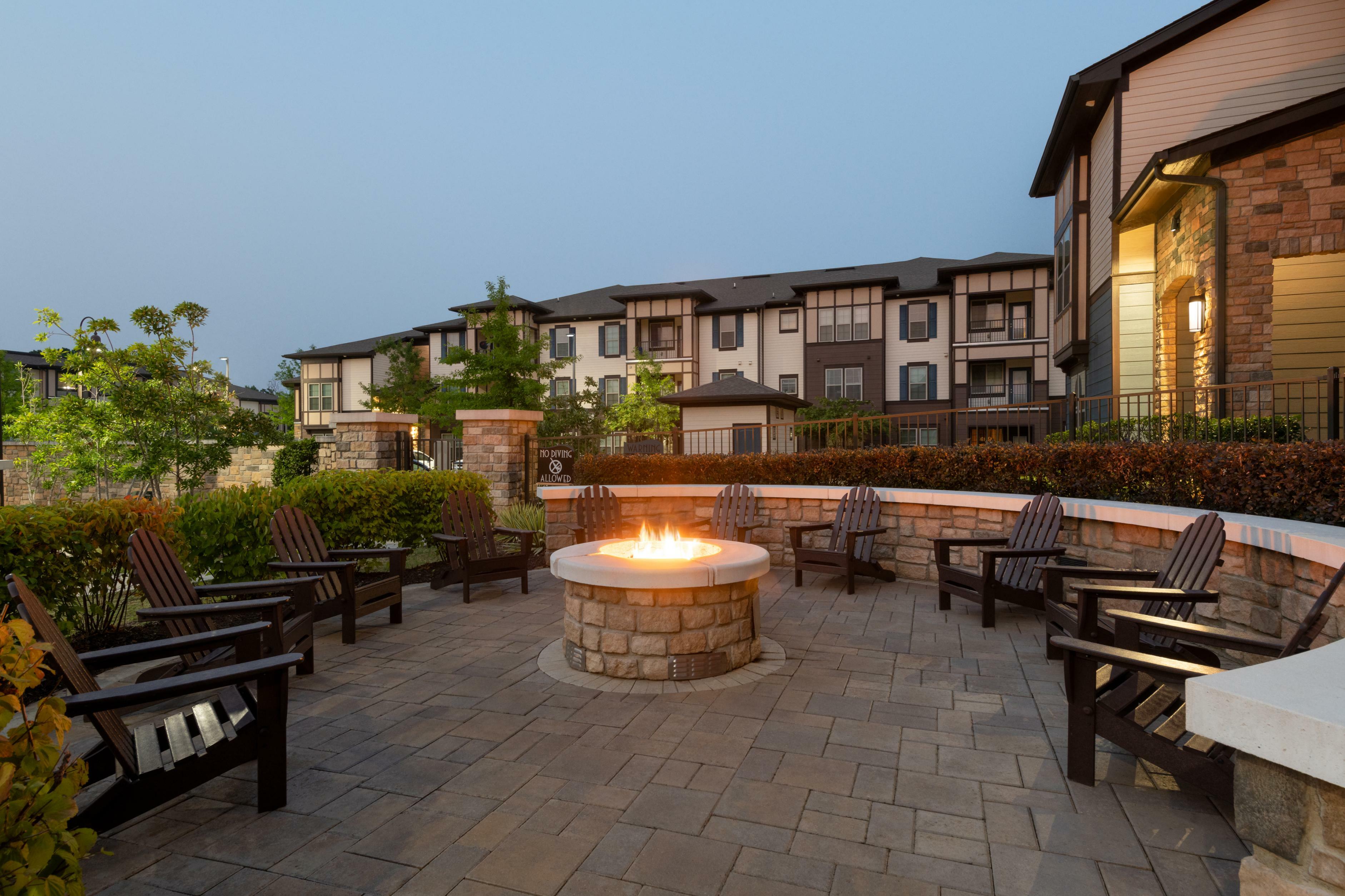 Inviting outdoor space with cozy fire pit surrounded by stylish seating, set against elegant apartment architecture.