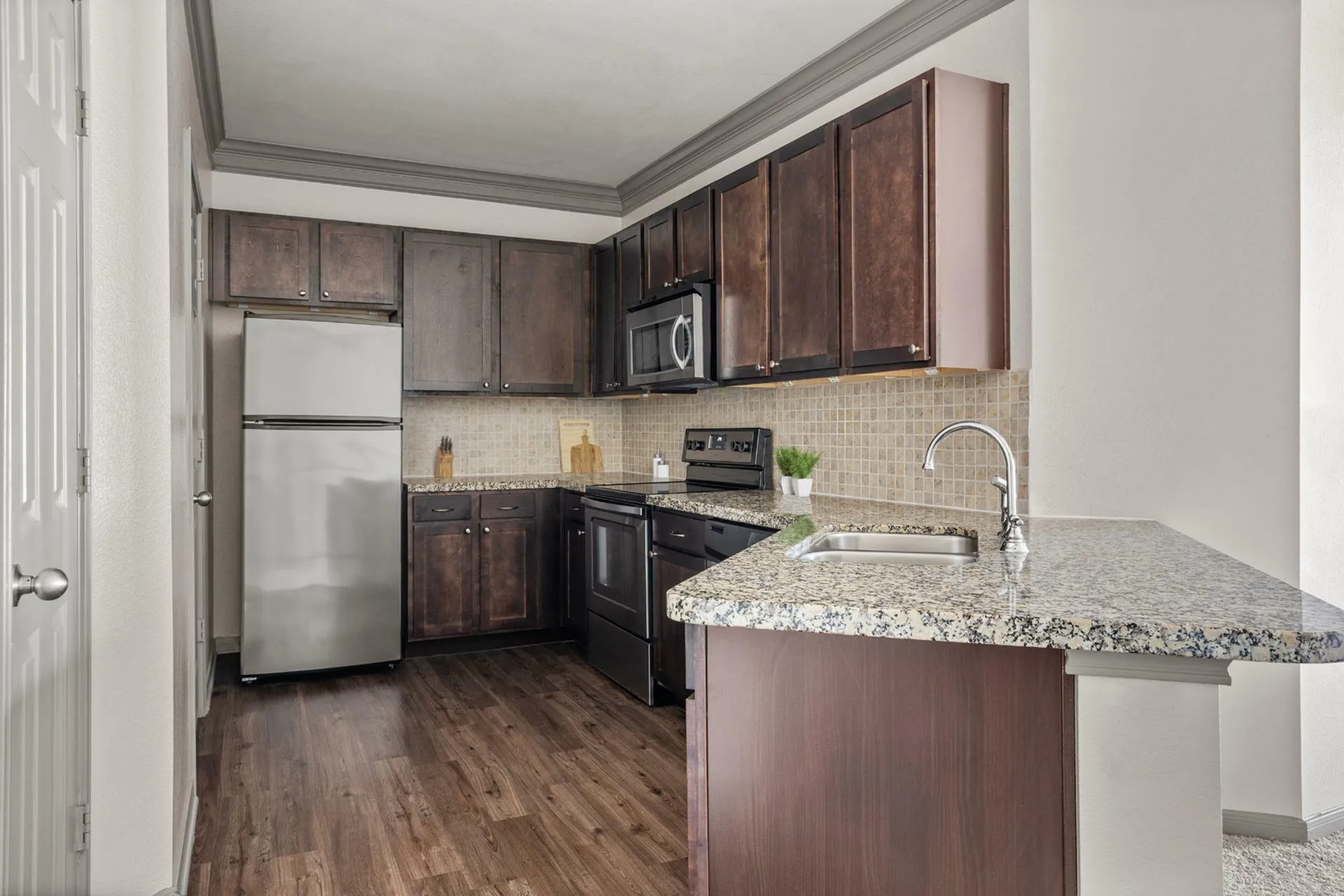 Modern kitchen with sleek dark wood cabinetry, granite countertops, and stainless steel appliances for a stylish home atmosphere.