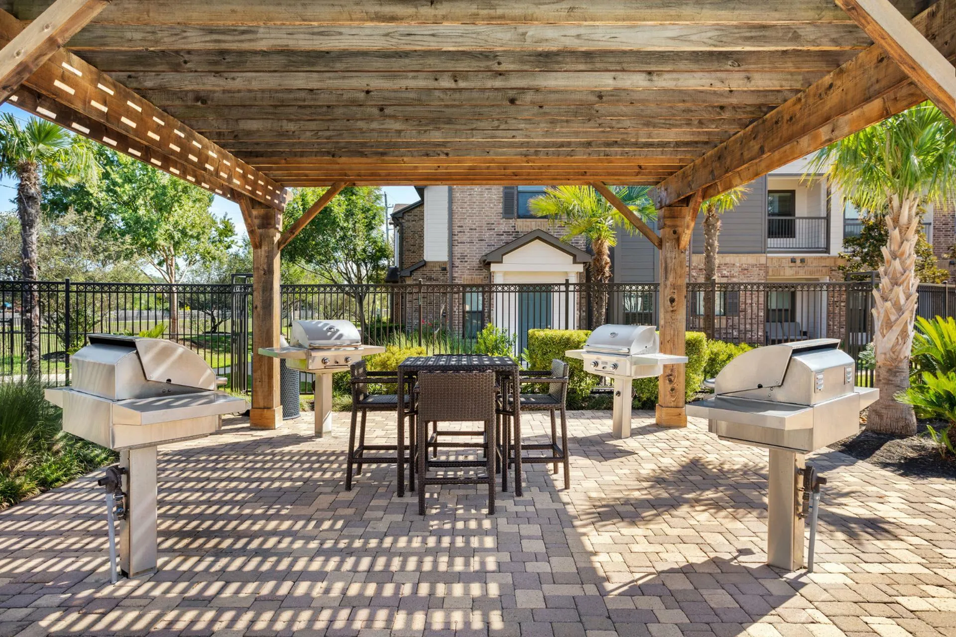 Charming outdoor grilling area with elegant pergola, featuring modern barbecue grills and cozy seating, surrounded by lush greenery.