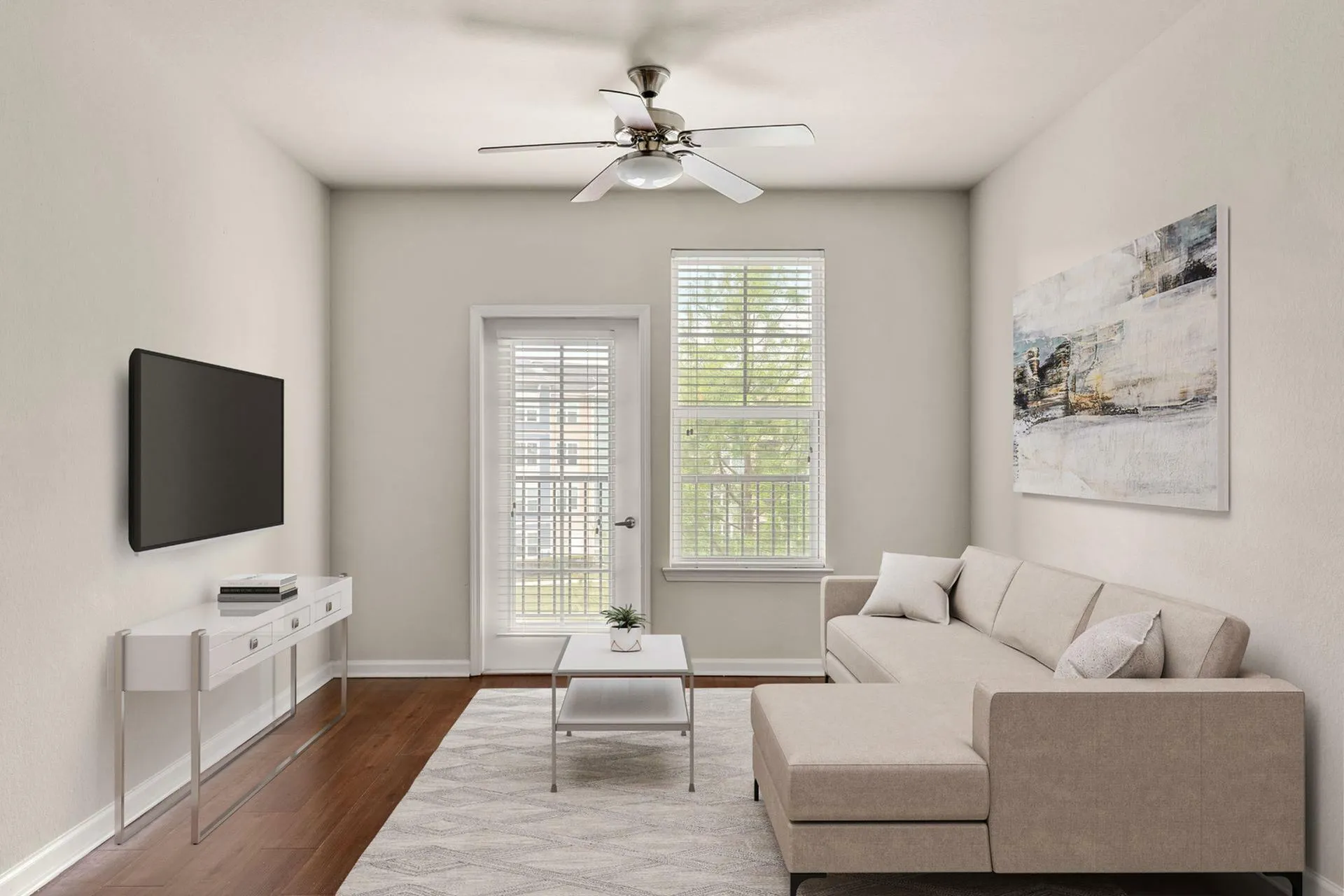 Sleek and modern living room with neutral-toned sofa, wall-mounted TV, and elegant ceiling fan, creating a serene and stylish atmosphere.