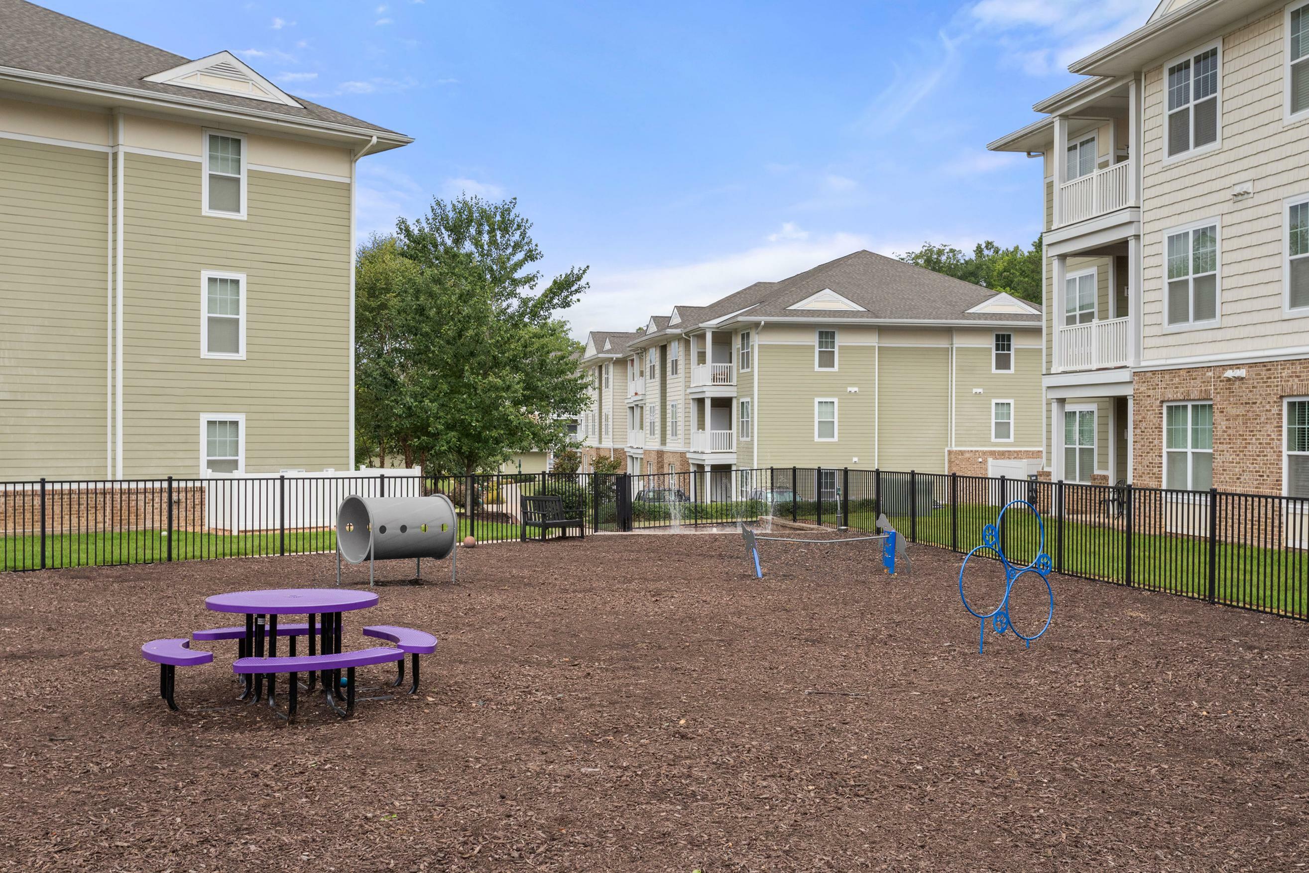 Charming apartment complex showcasing a vibrant outdoor playground with modern play equipment surrounded by lush greenery.