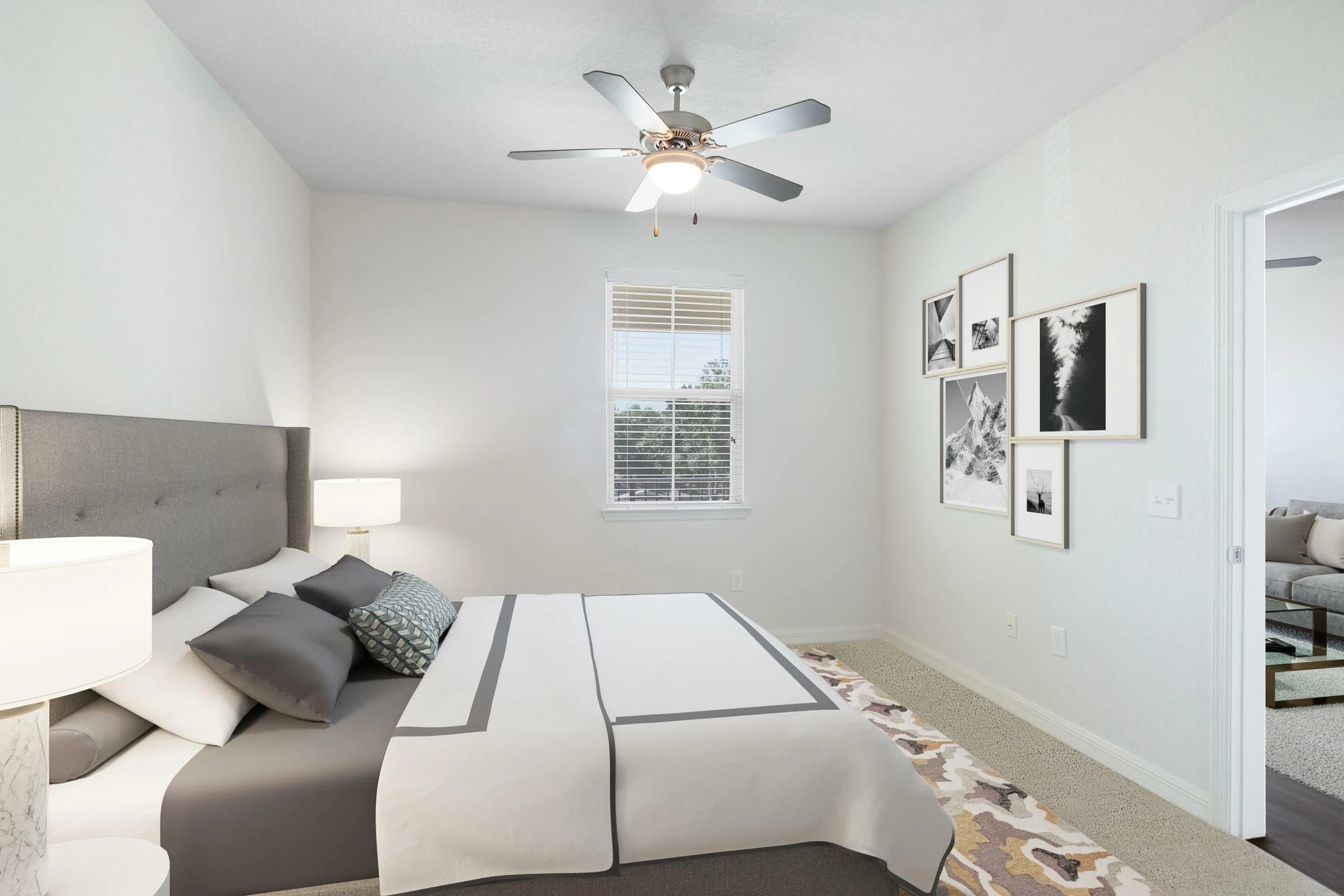 Bright bedroom with modern ceiling fan, stylish gray and white bedding, and artistic gallery wall. Natural light flows through large window, complementing the elegant decor.
