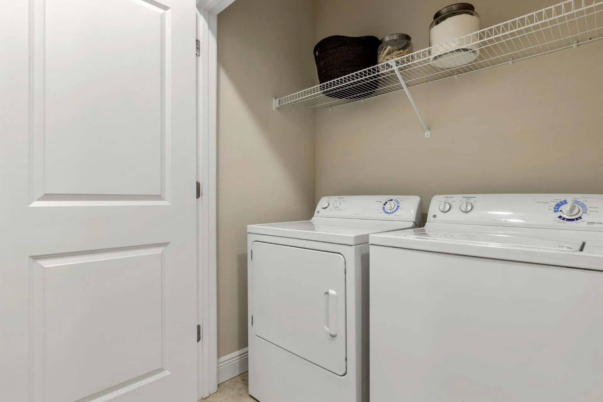 Chic home laundry room with modern washer and dryer set, featuring ample shelving for storage.