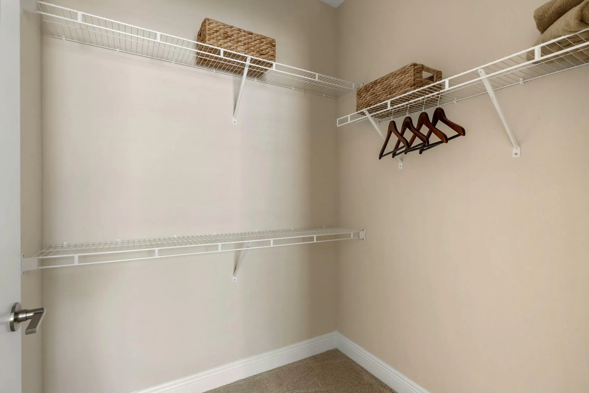 Spacious walk-in closet with elegant wire shelving and wooden hangers, perfect for organized storage.