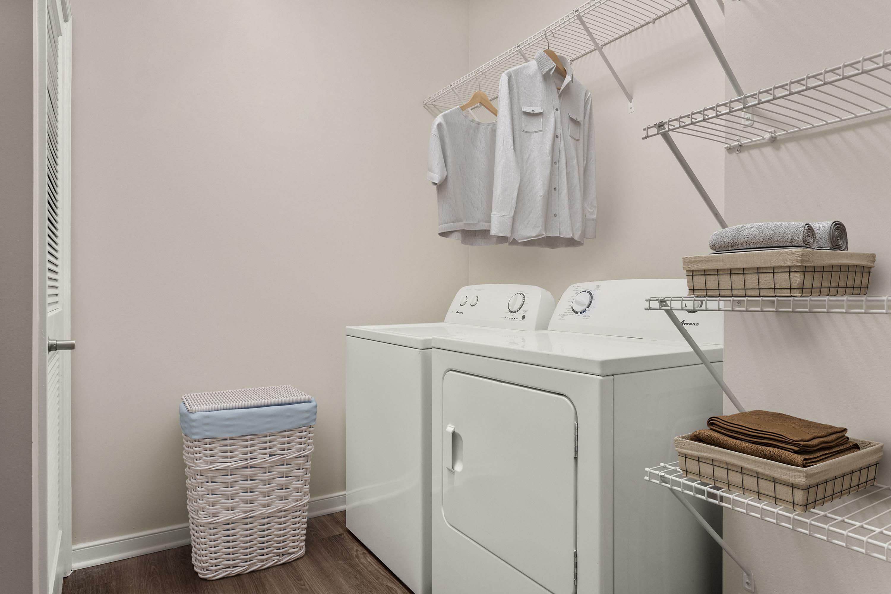 Modern laundry room with sleek washer and dryer, organized shelving, and stylish clothing storage.