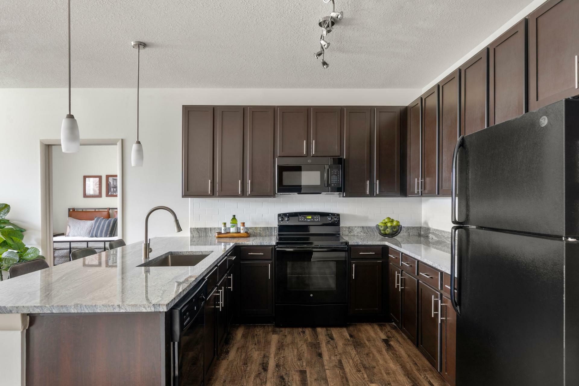 Modern kitchen with elegant dark wood cabinets, sleek granite countertops, and contemporary appliances in an open-concept space.
