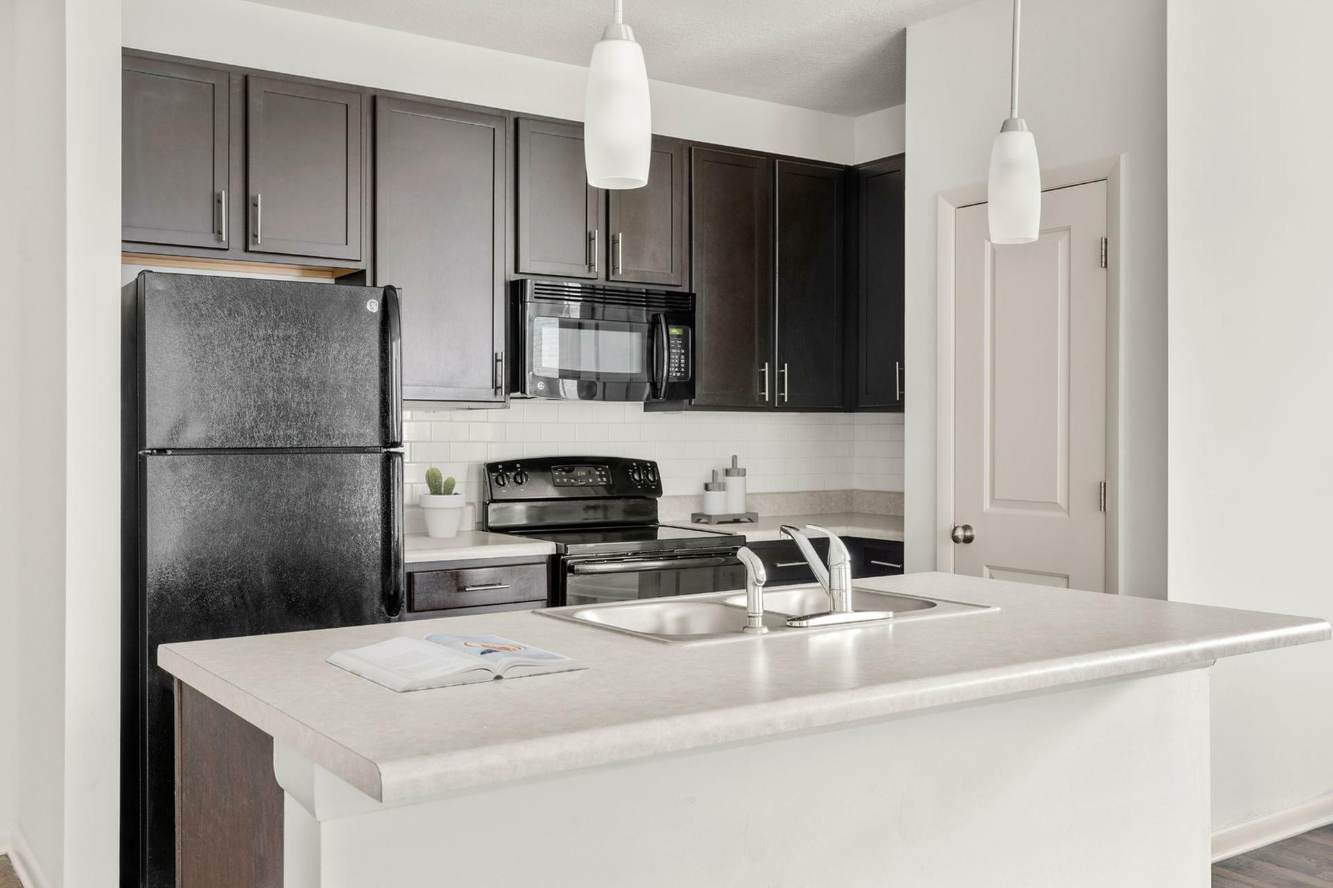 Modern kitchen with sleek dark cabinetry, integrated appliances, and a stylish island with pendant lighting.