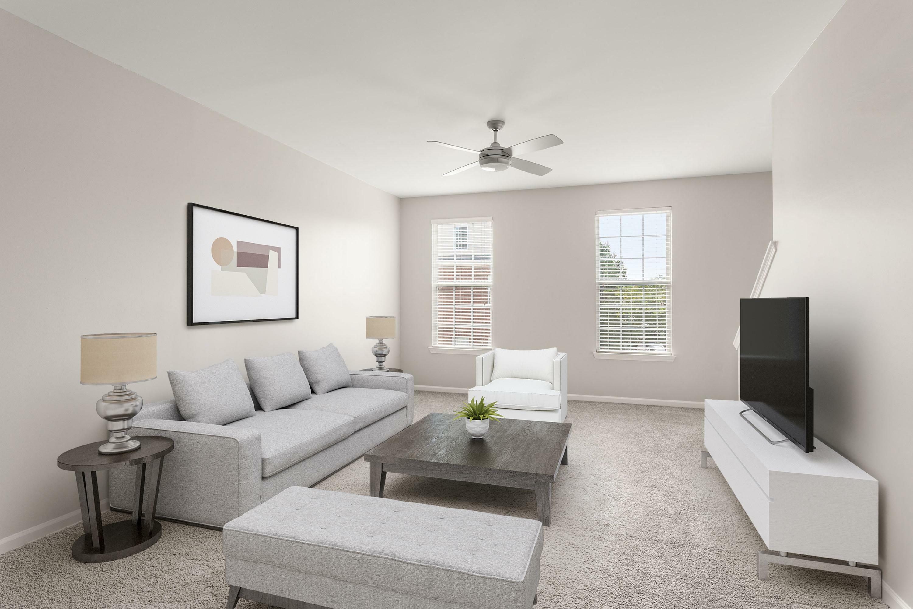 Bright and modern living room with plush gray seating, a chic coffee table, and natural light streaming through large windows.