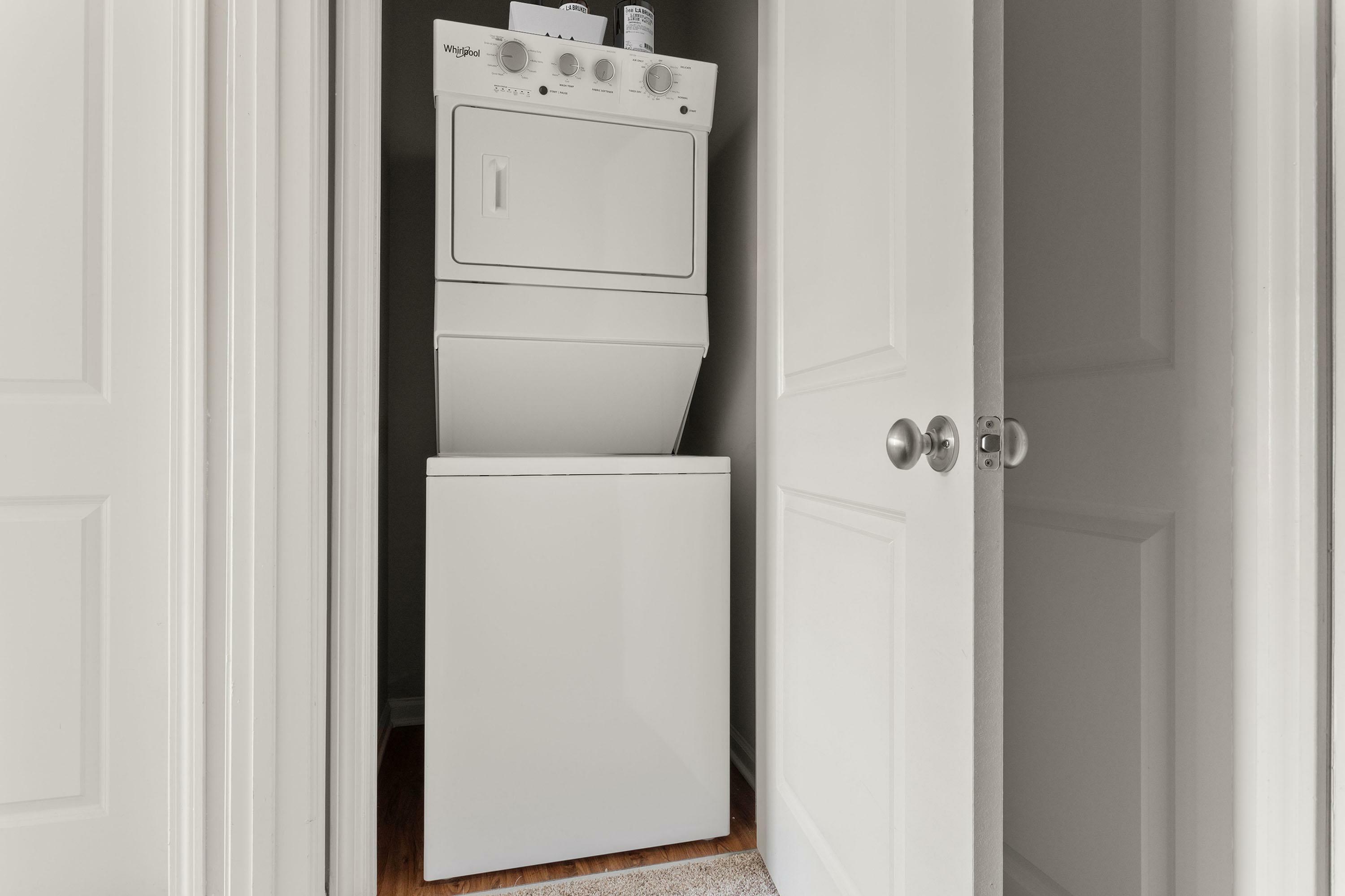 Compact laundry area with a modern stacked washer and dryer behind double white doors, optimizing space and convenience.