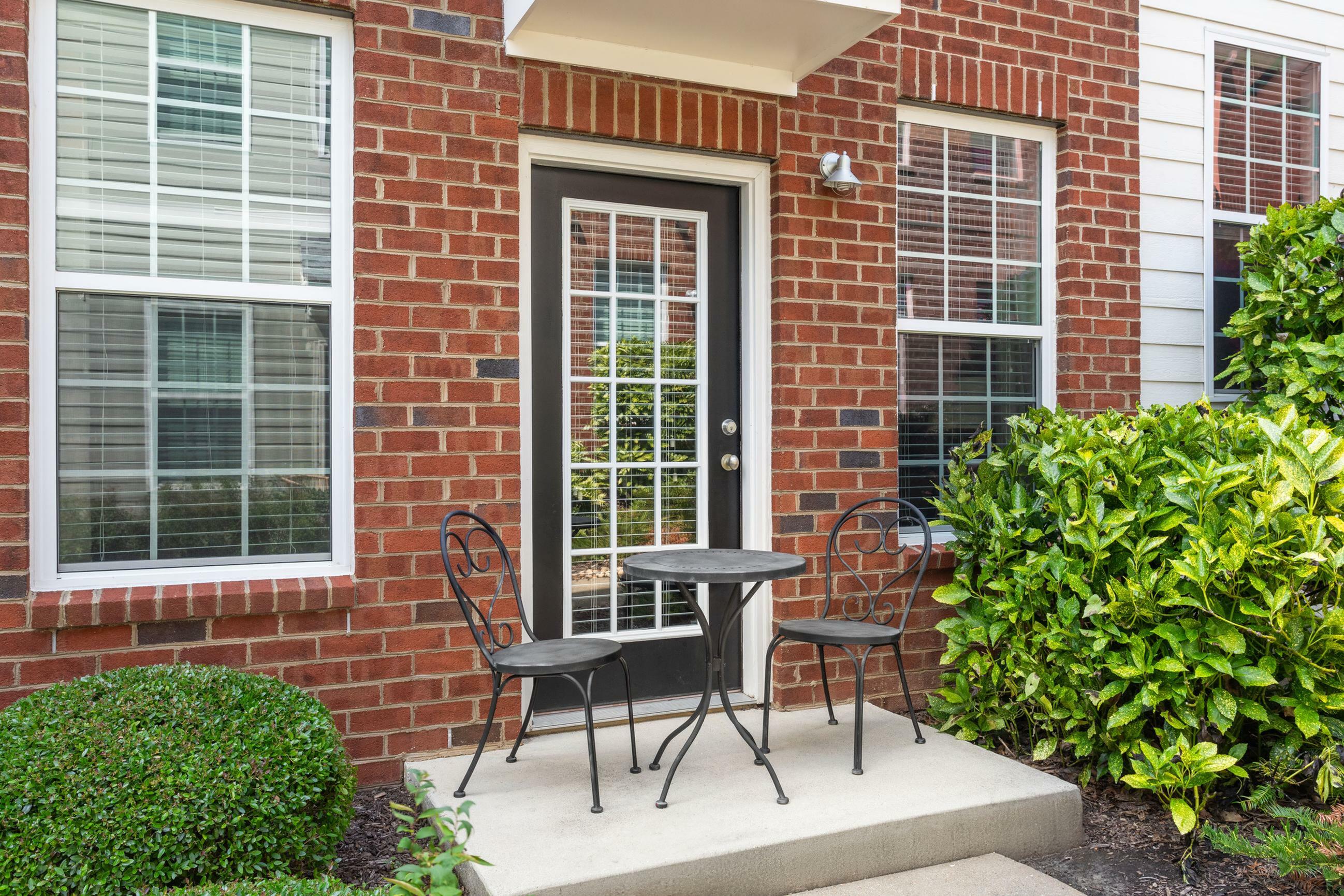 Charming brick patio with a cozy bistro set and lush green landscaping, perfect for relaxation and outdoor enjoyment.