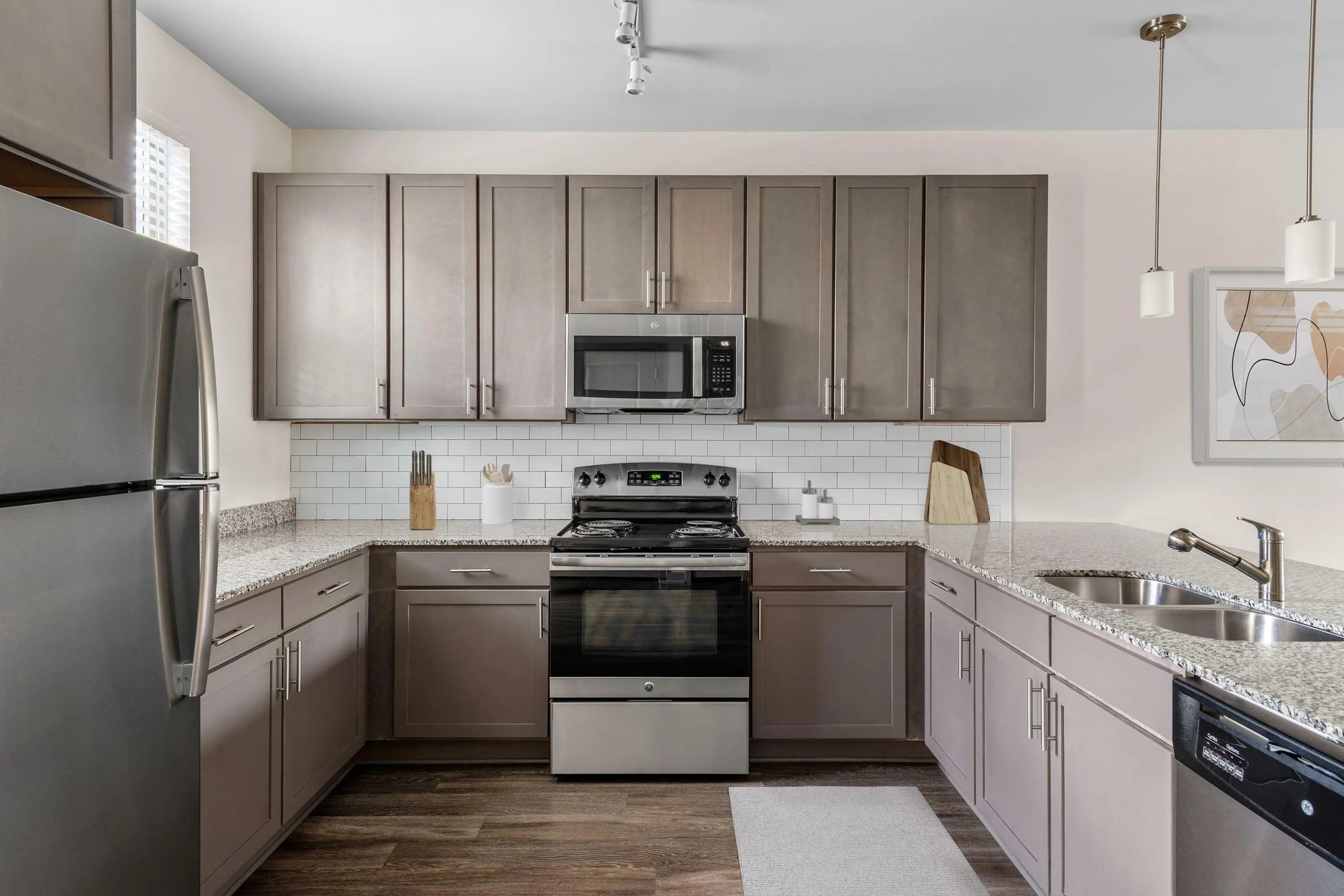Modern kitchen with sleek grey cabinets, granite countertops, stainless steel appliances, and stylish track lighting.
