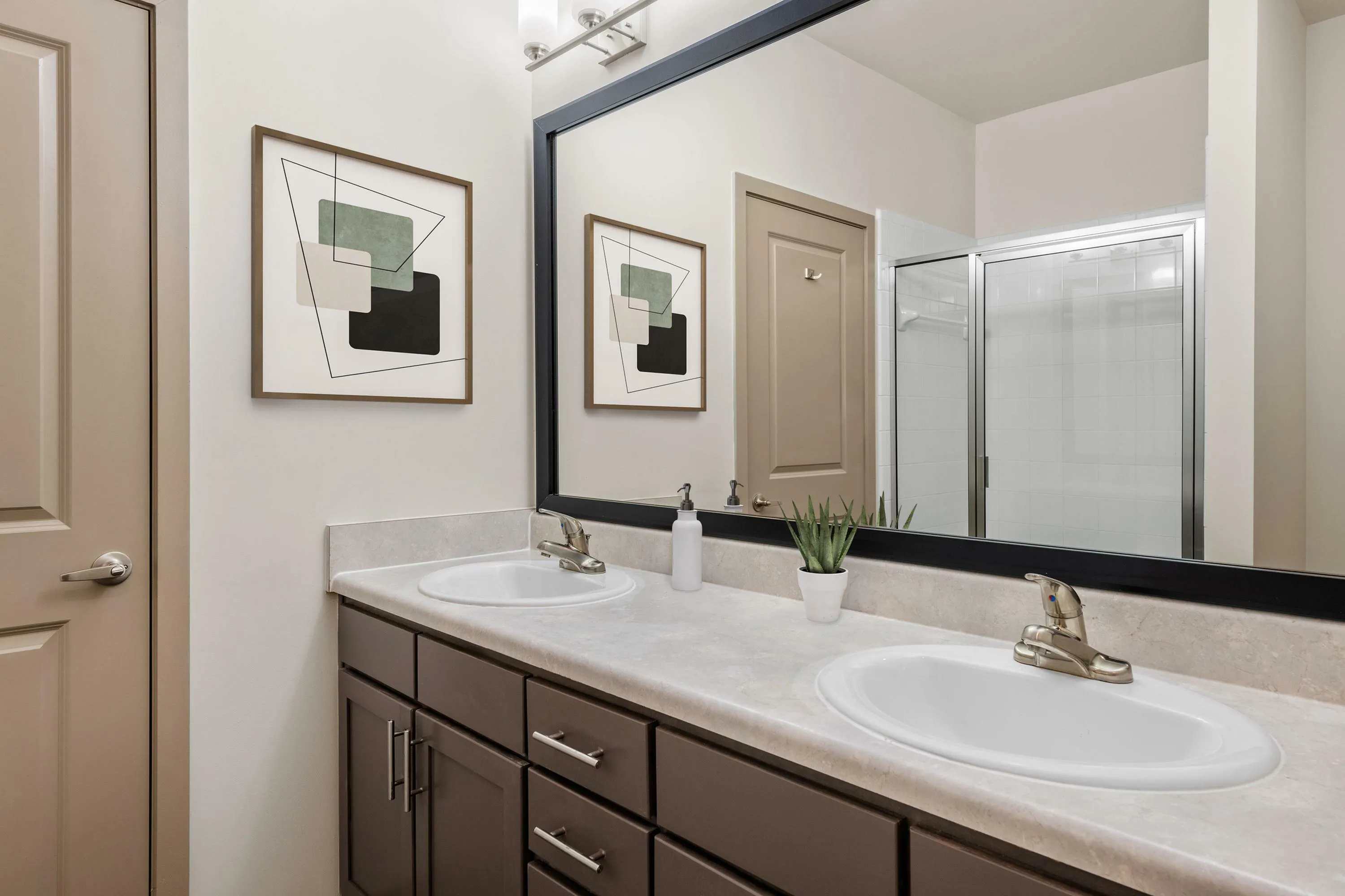 Elegant and modern bathroom featuring a double vanity with sleek fixtures, a large framed mirror, and minimalistic decor.