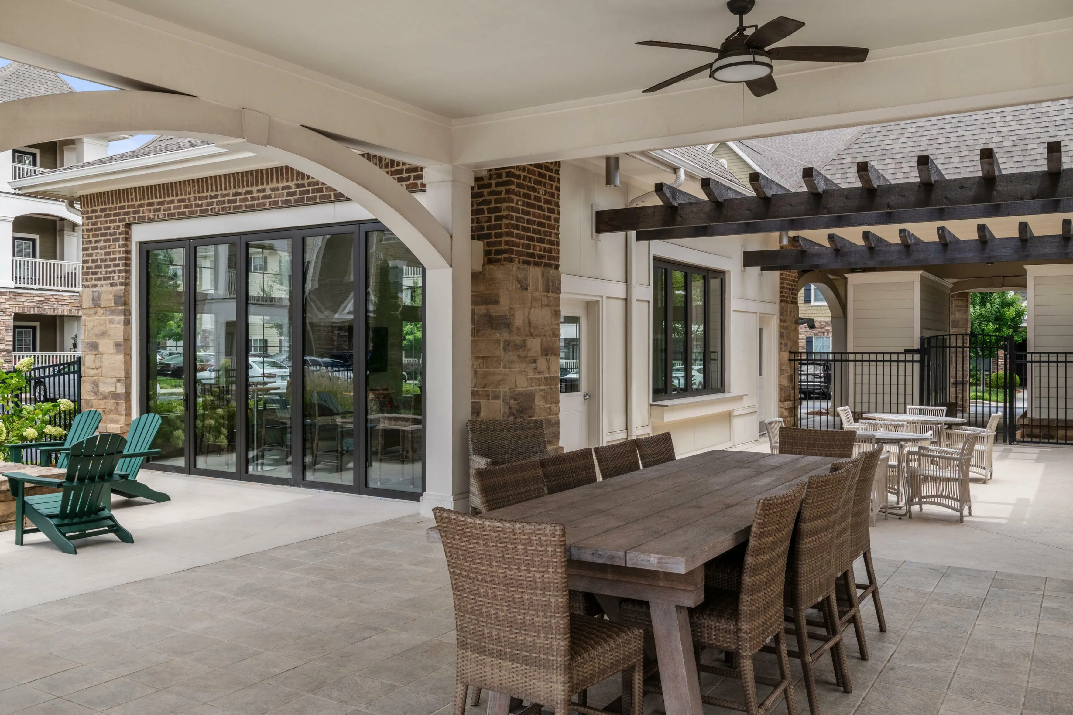Charming outdoor lounge with rustic wooden dining set, wicker chairs, and lush greenery views, perfect for entertaining.