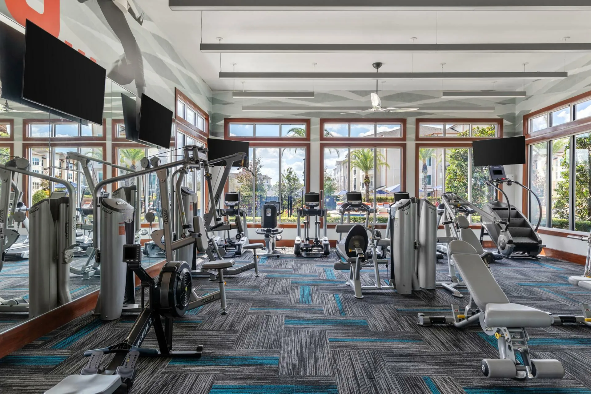 Modern fitness center with state-of-the-art gym equipment and large windows offering scenic outdoor views.
