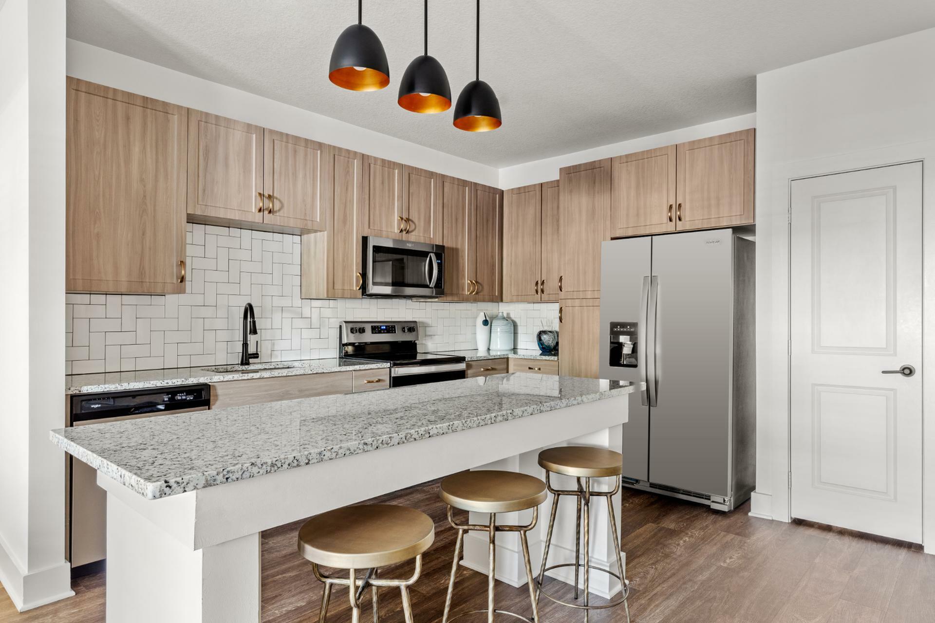 Modern kitchen with sleek granite countertops, stainless steel appliances, elegant wooden cabinetry, and stylish pendant lighting over a breakfast bar with chic seating.