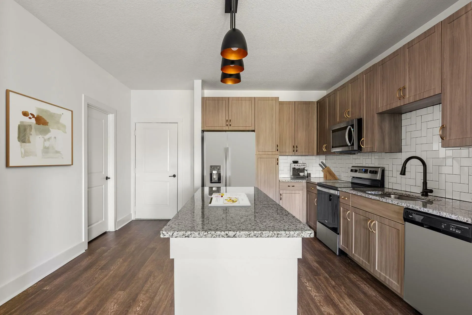 Elegant kitchen design with granite countertops, sleek stainless steel appliances, and modern wood cabinetry under stylish pendant lighting.