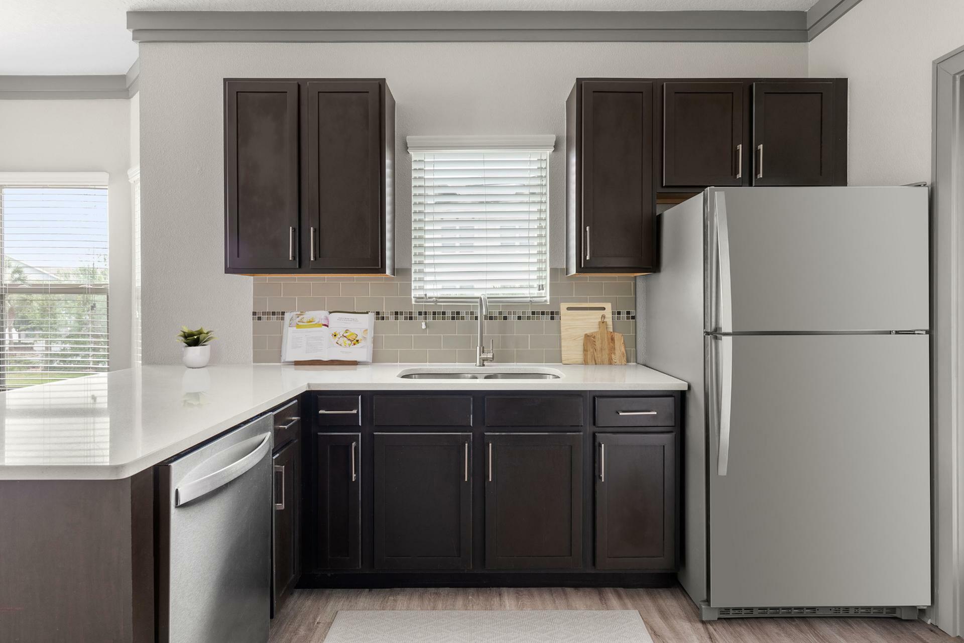 Modern kitchen with elegant dark wood cabinets, sleek stainless steel appliances, and bright natural light creating an inviting cooking space.