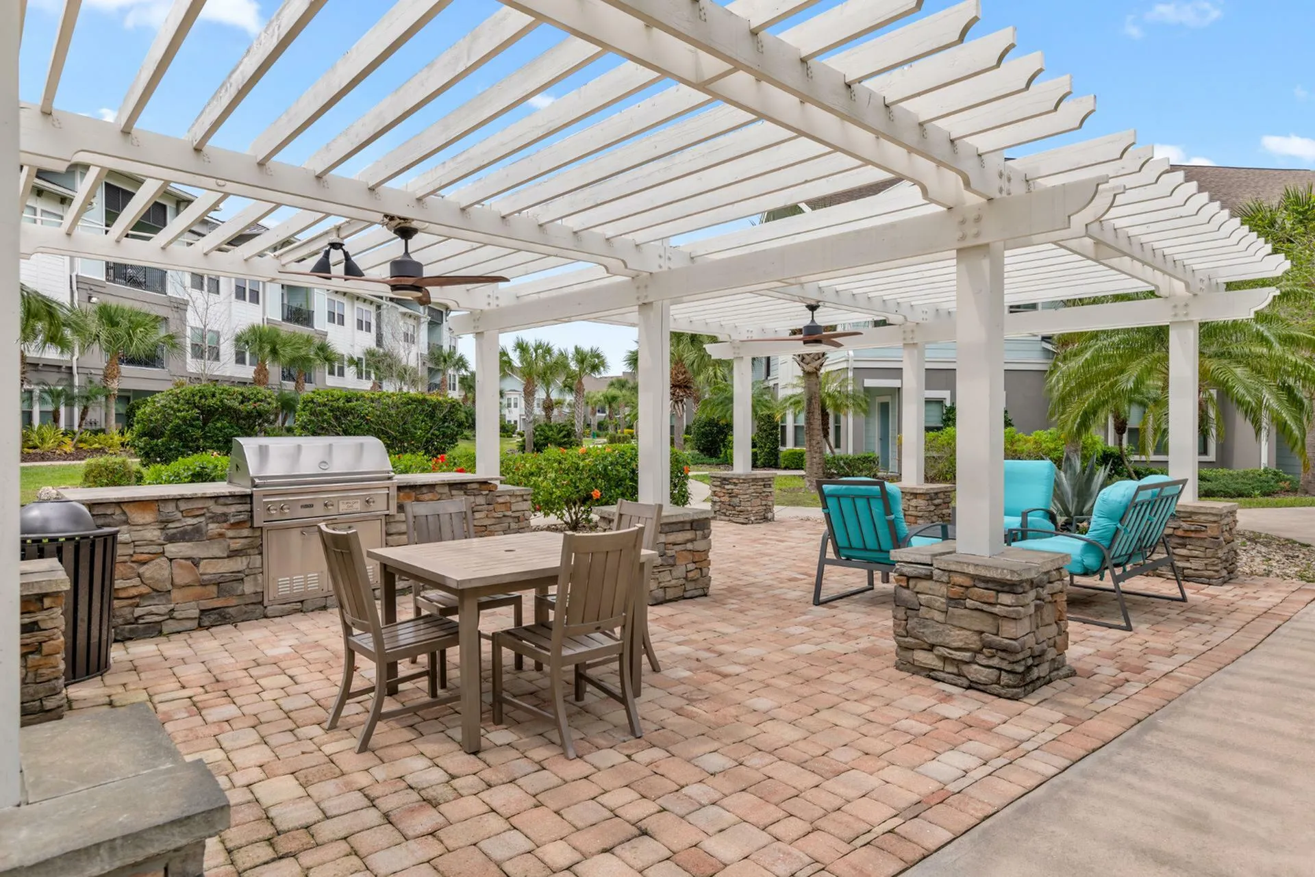 Charming outdoor patio with elegant pergola, cozy seating area, and modern grill set amidst lush landscaping.