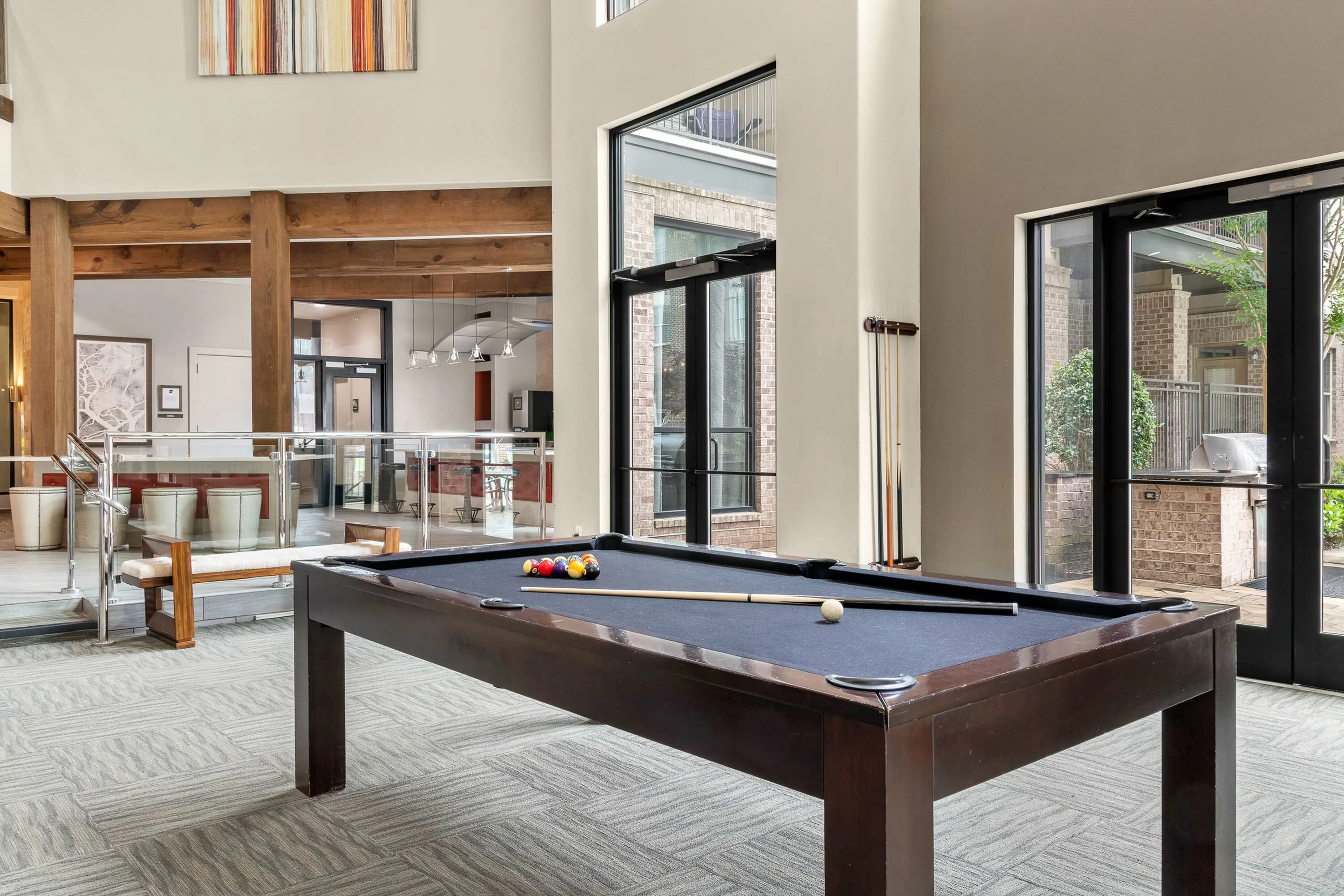 Inviting recreation space featuring a stylish pool table, modern decor, and bright natural lighting.