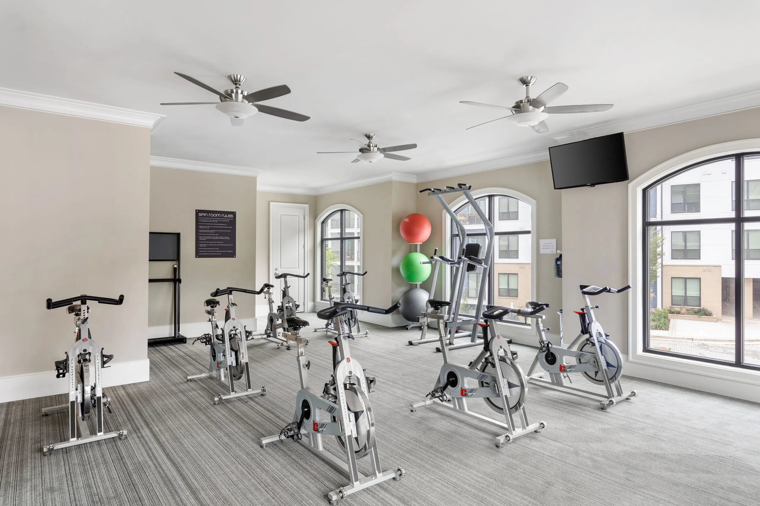 Modern fitness center featuring spin bikes, exercise equipment, and bright windows inviting natural light.
