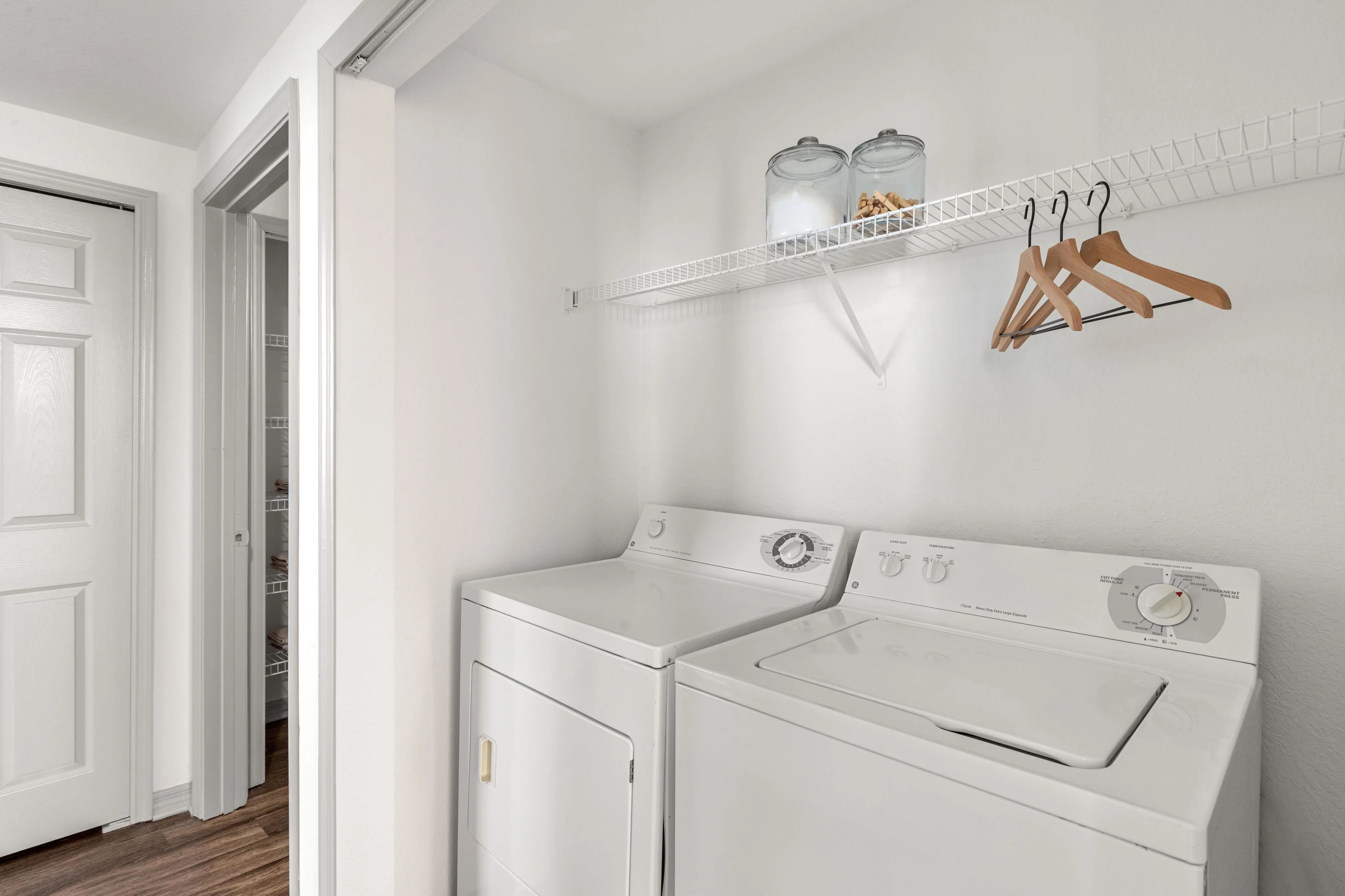 Bright laundry room with modern washer and dryer, open shelving, and stylish hangers.